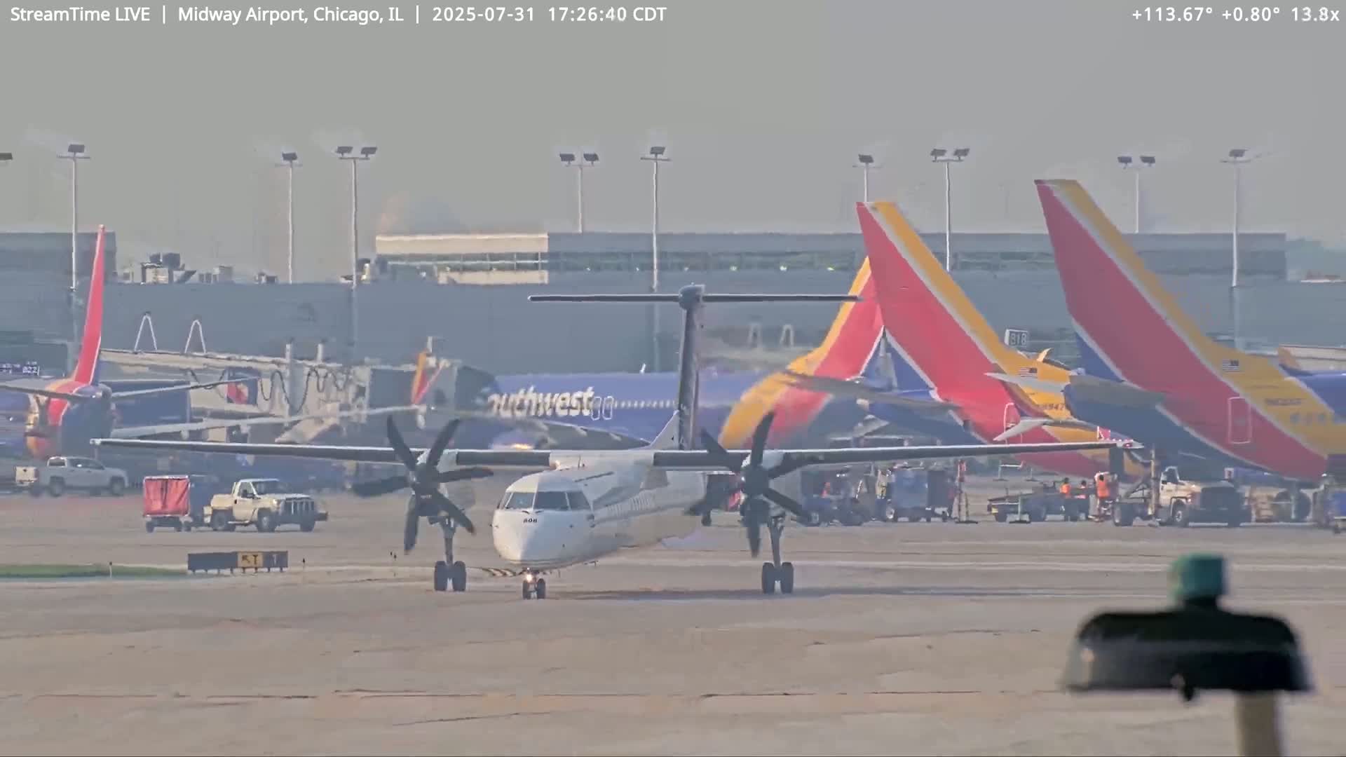 A turboprop airplane taxis on an airport tarmac on a hazy day, past several Southwest Airlines jets.