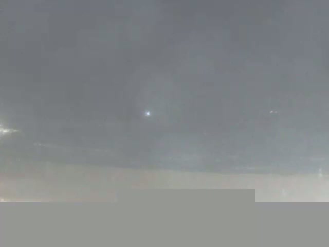 A bright light is visible in an overcast sky.