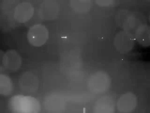 A blurry, nighttime image shows distant lights through heavy rain or fog.