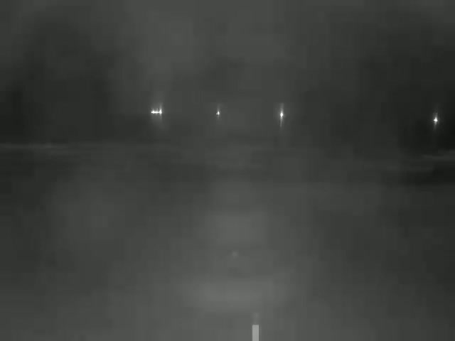 A dark, nighttime scene shows a road with faint lights in the distance and a blurry foreground.