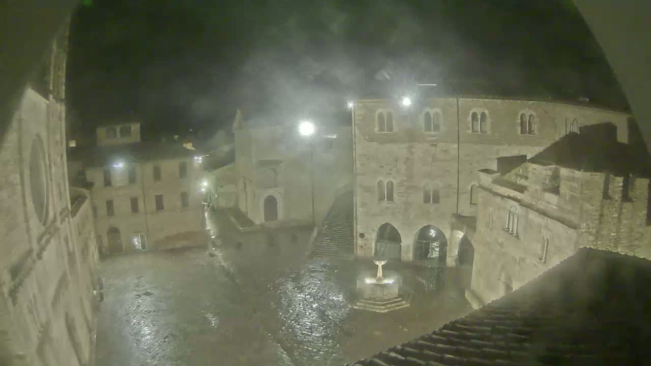 A rain-soaked town square at night, surrounded by ancient stone buildings under a misty sky.