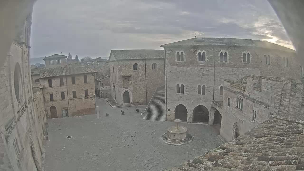 A mostly empty stone plaza, surrounded by aged buildings, on an overcast day.