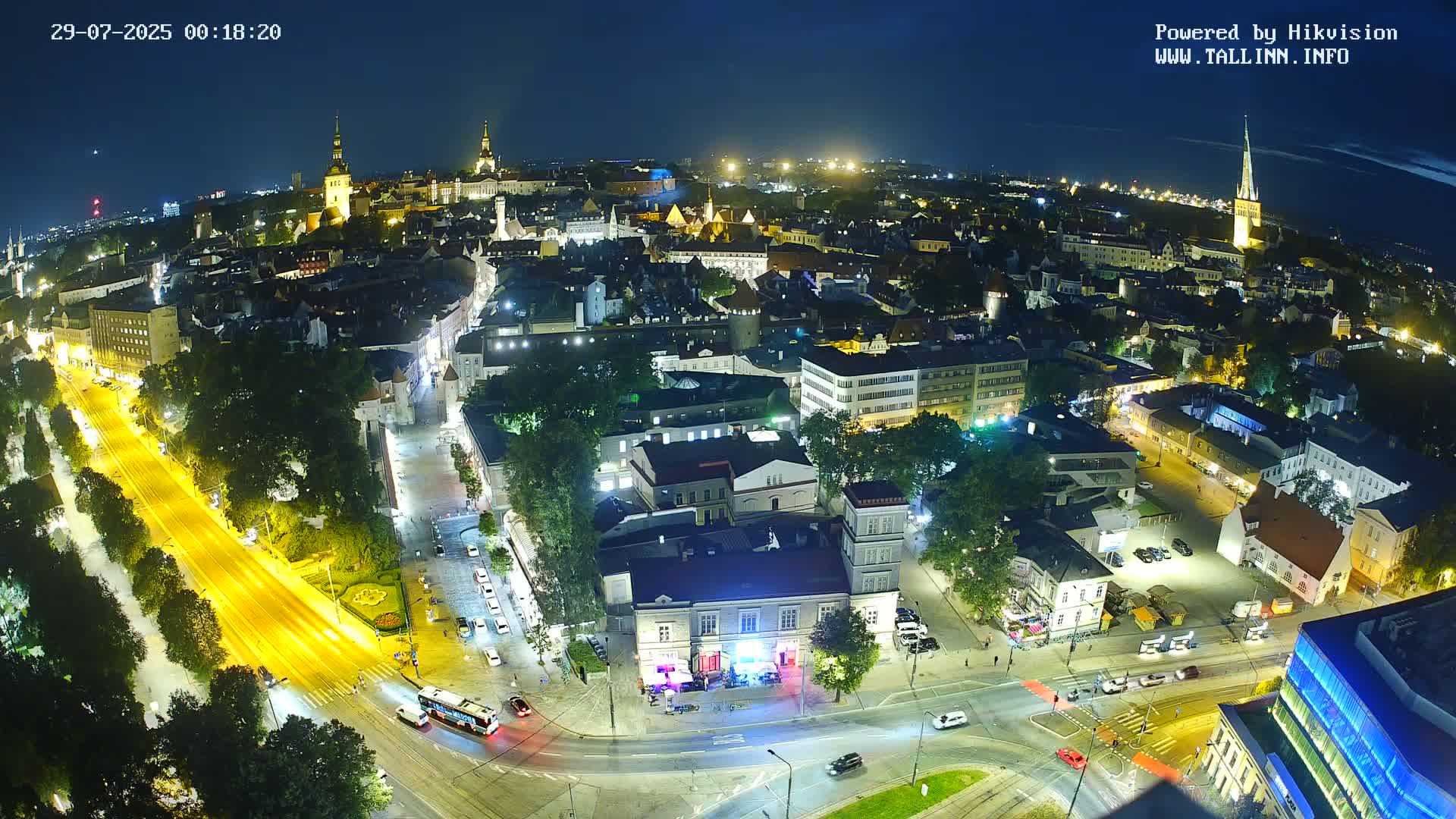 A nighttime aerial view of a city illuminated by streetlights and building lights, under a clear, dark sky.