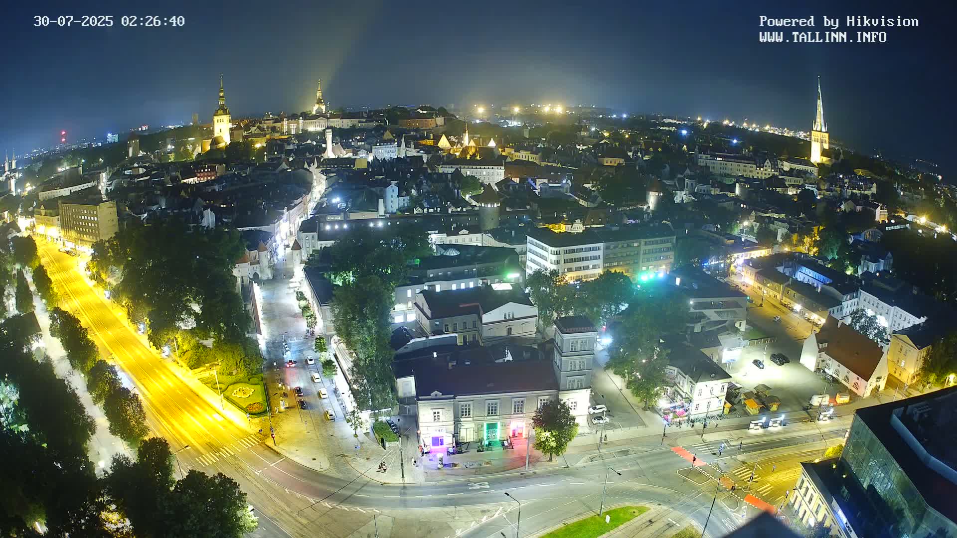 A nighttime aerial view of a city illuminated by streetlights and building lights, under a clear, dark sky.