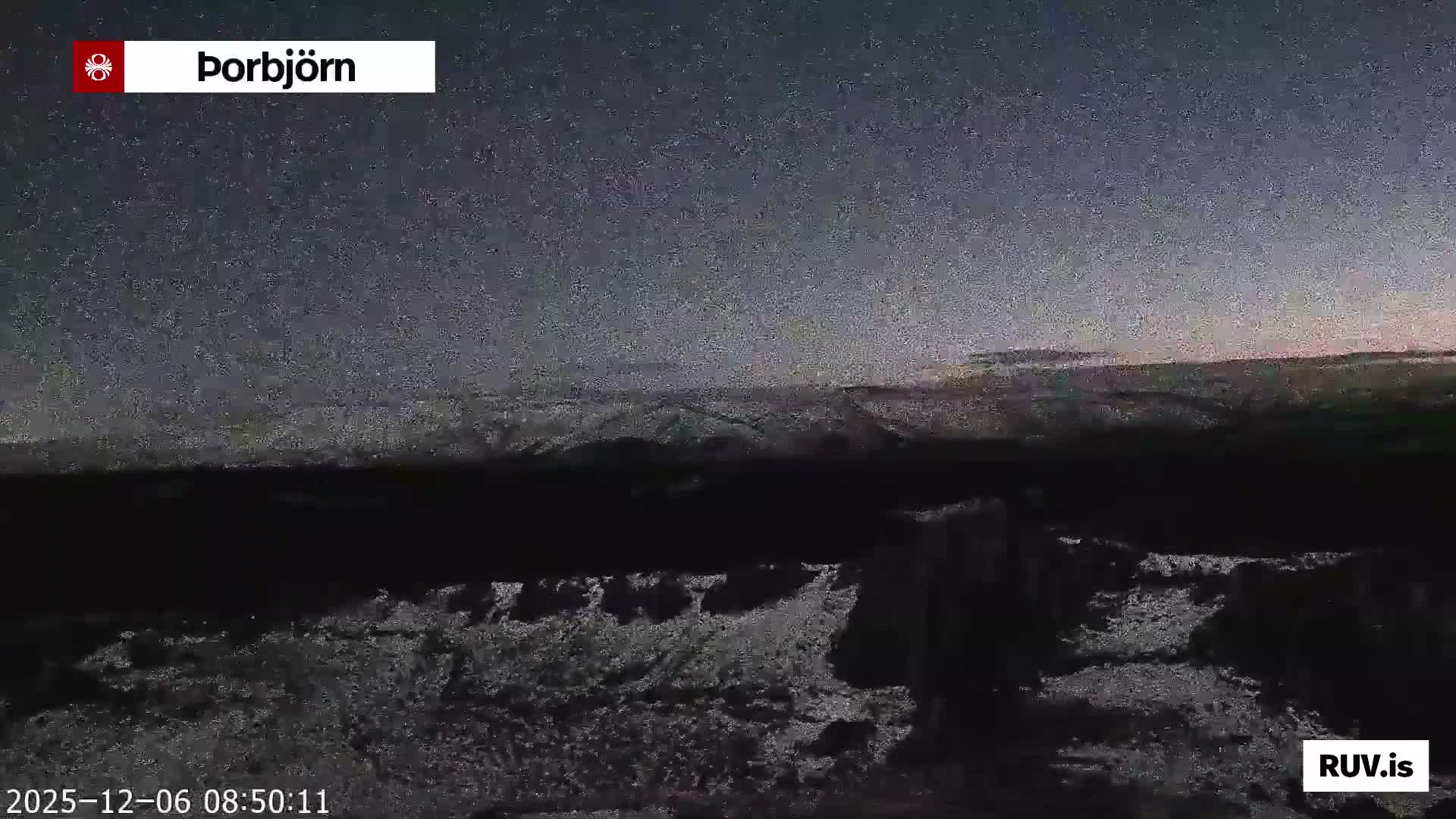 A cold, vast, and dark landscape, likely snow-covered, stretches under a speckled pre-dawn sky with a faint light emerging on the distant horizon.