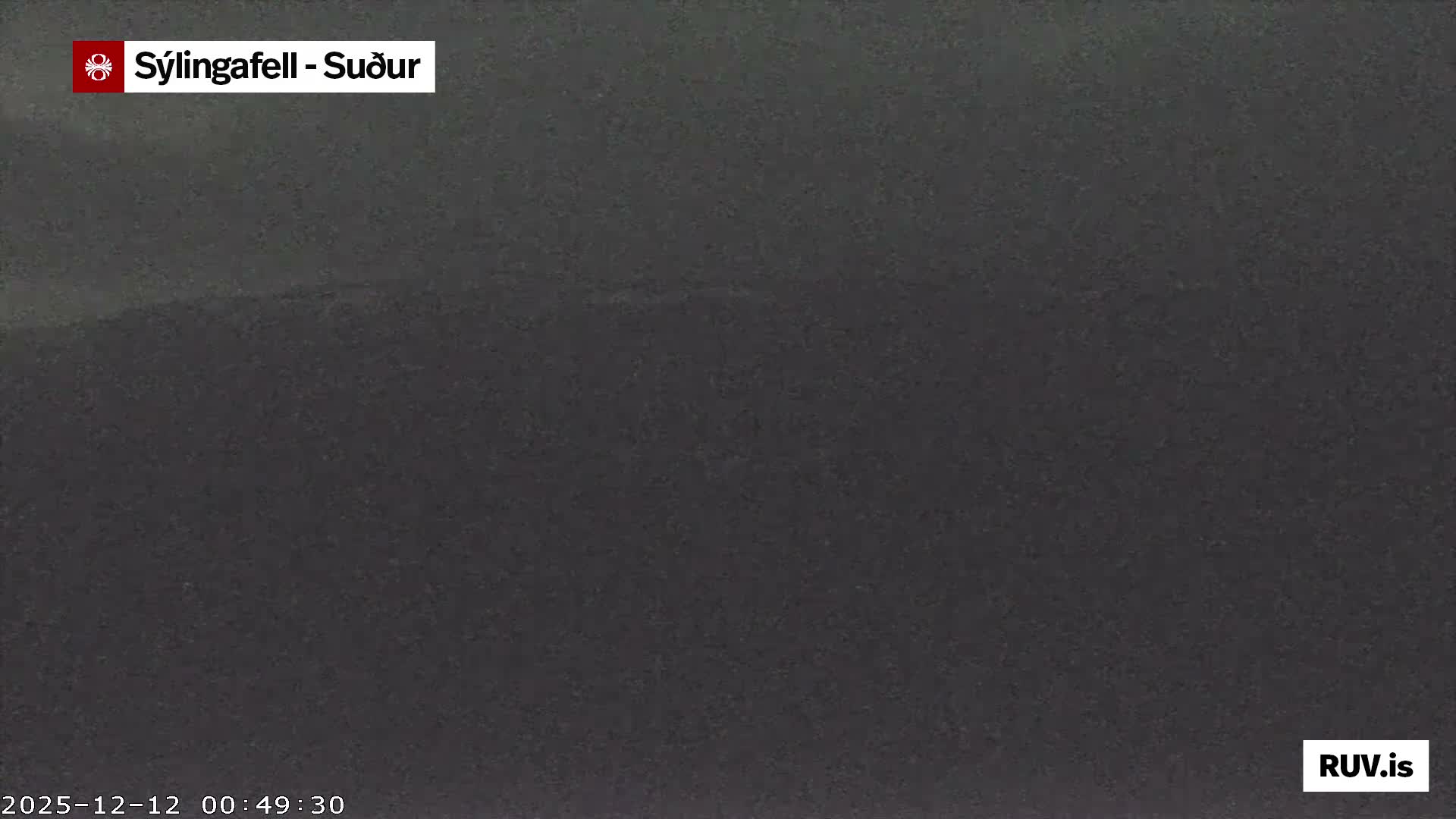 A dark, featureless outdoor scene is depicted in uniform shades of dark gray, suggesting an extremely low visibility night due to dense fog or heavy overcast conditions.