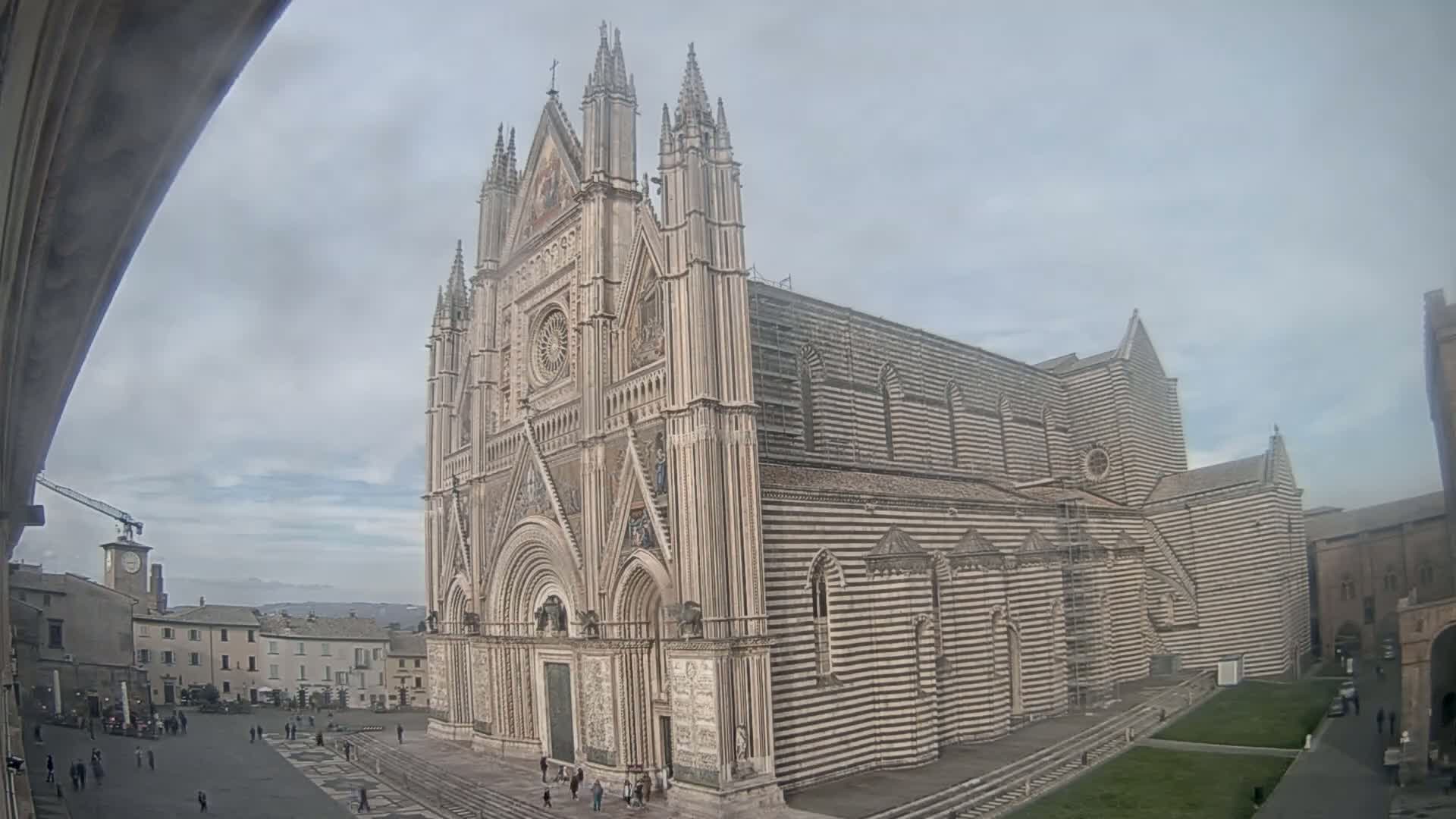 A large, striped cathedral stands in a town square on an overcast day.