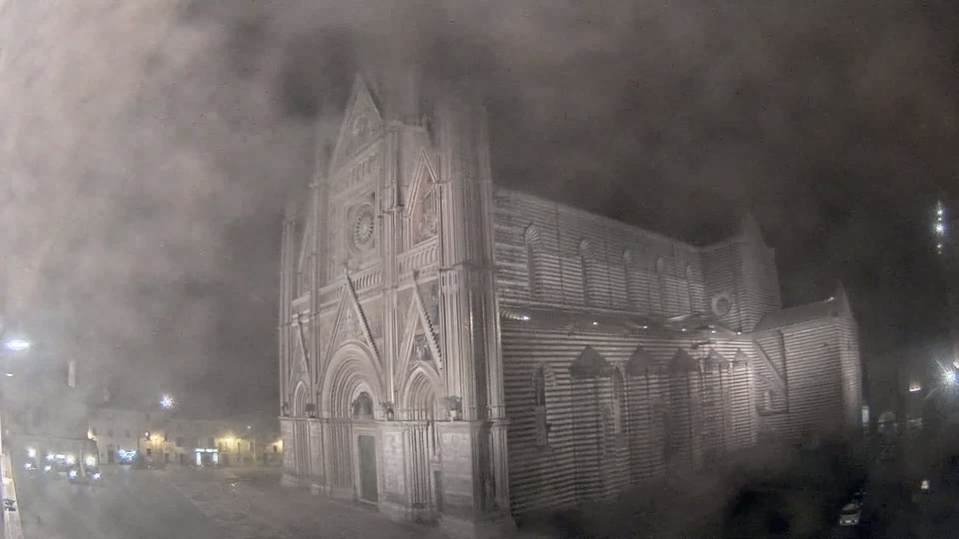 A large, striped stone cathedral is visible at night through a thick fog.