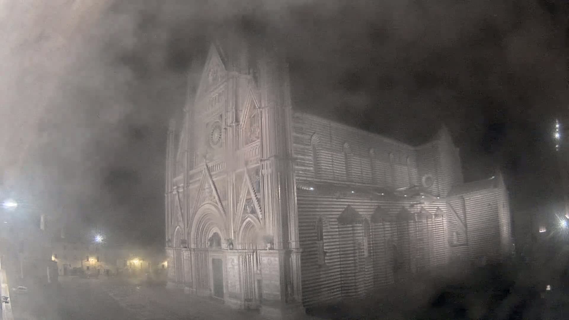 A large, gothic-style cathedral is partially obscured by a thick fog at night.