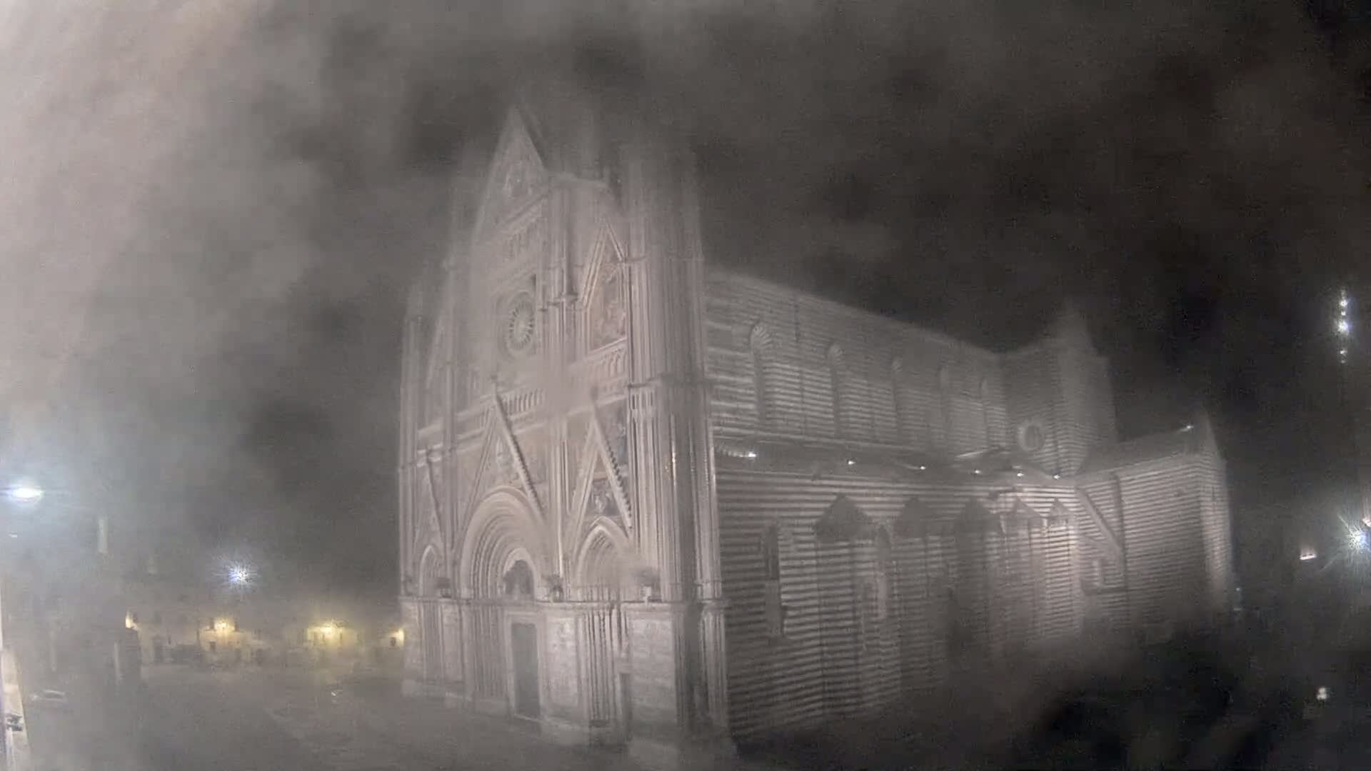 A large, ornate cathedral is shrouded in thick fog at night.