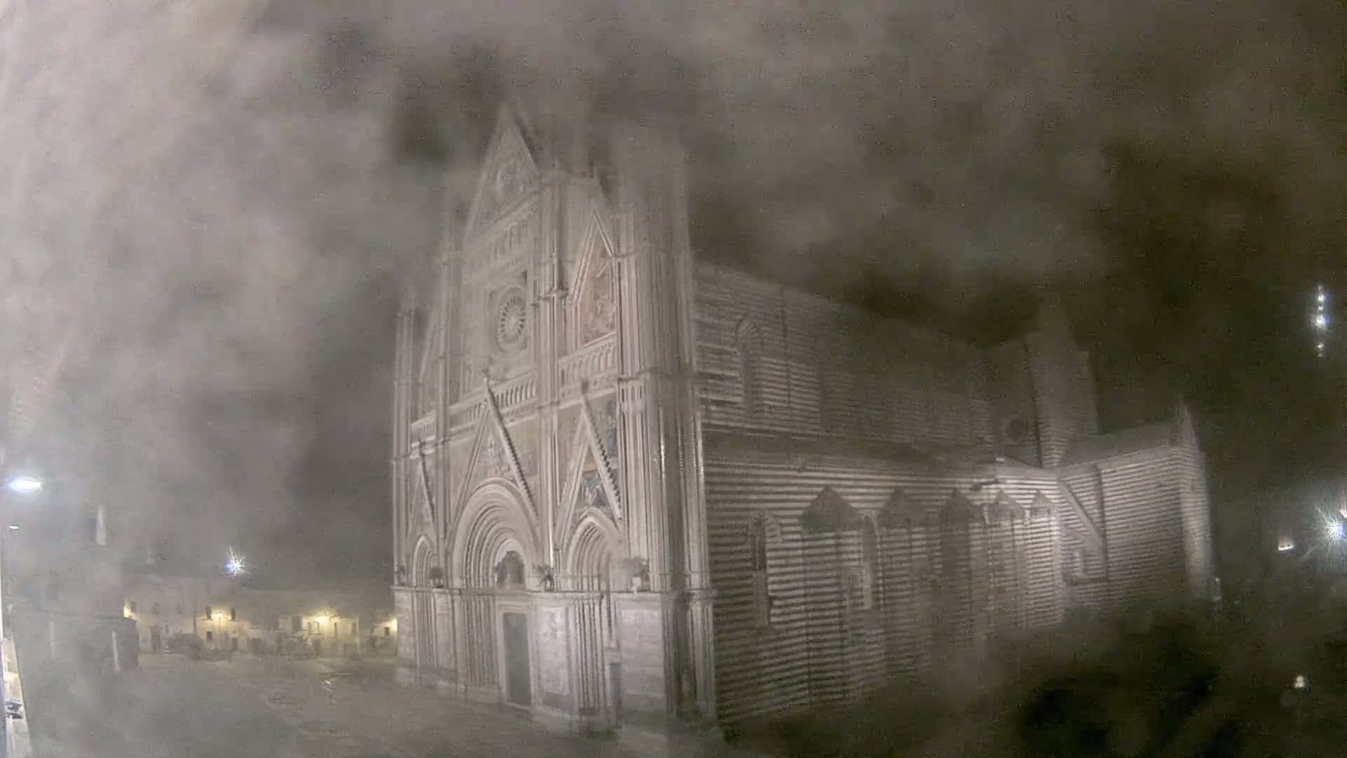 A large, ornate stone church is shrouded in thick fog at night.
