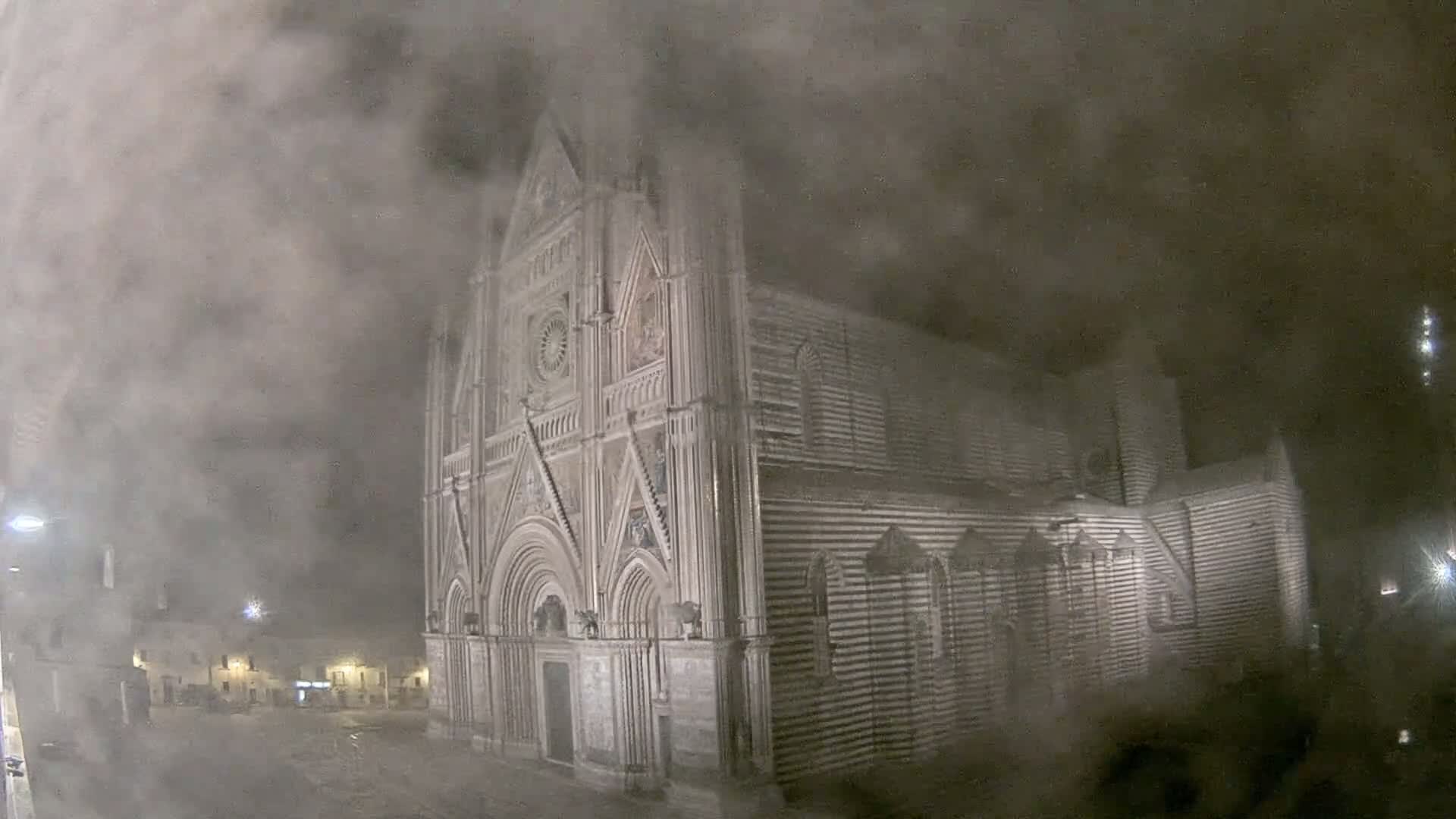 A large, striped stone cathedral is partially obscured by heavy fog or snow at night.