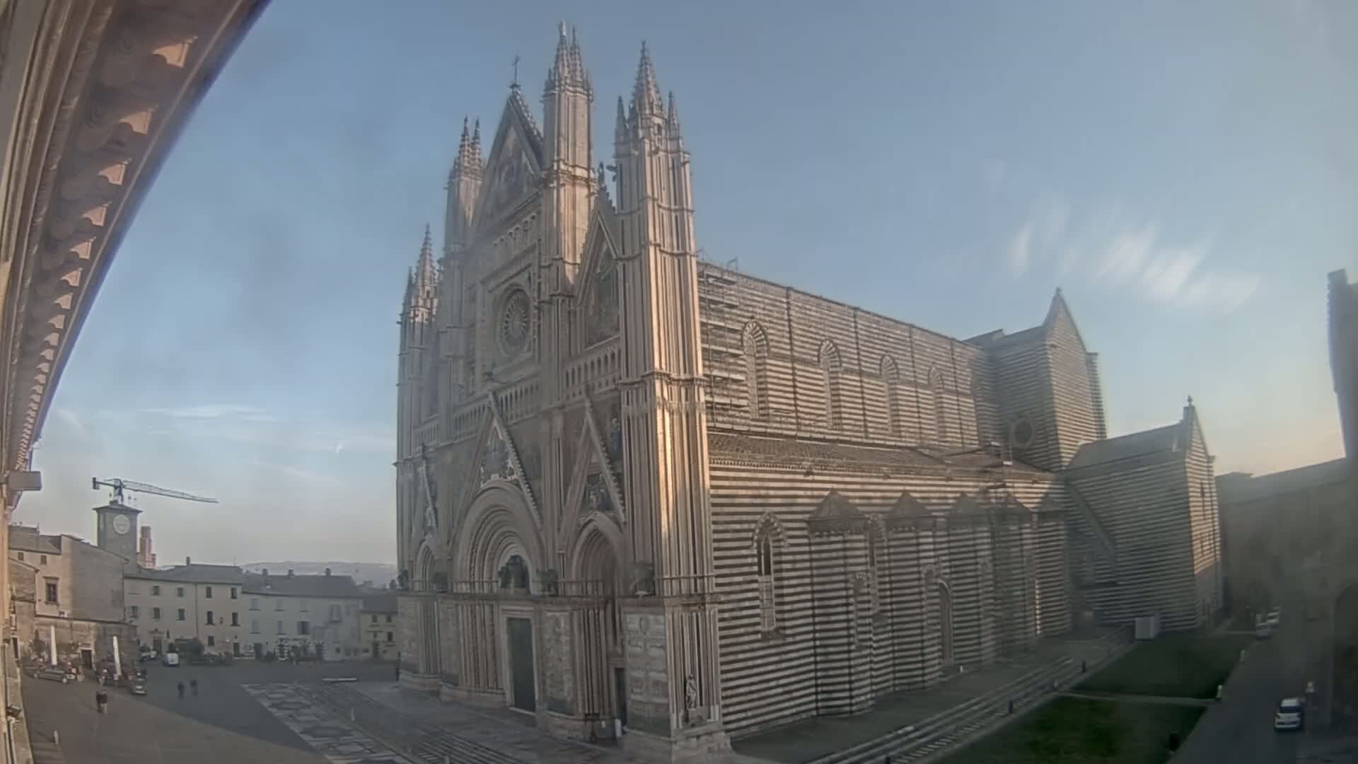 A large striped cathedral stands in a town square on a clear day.