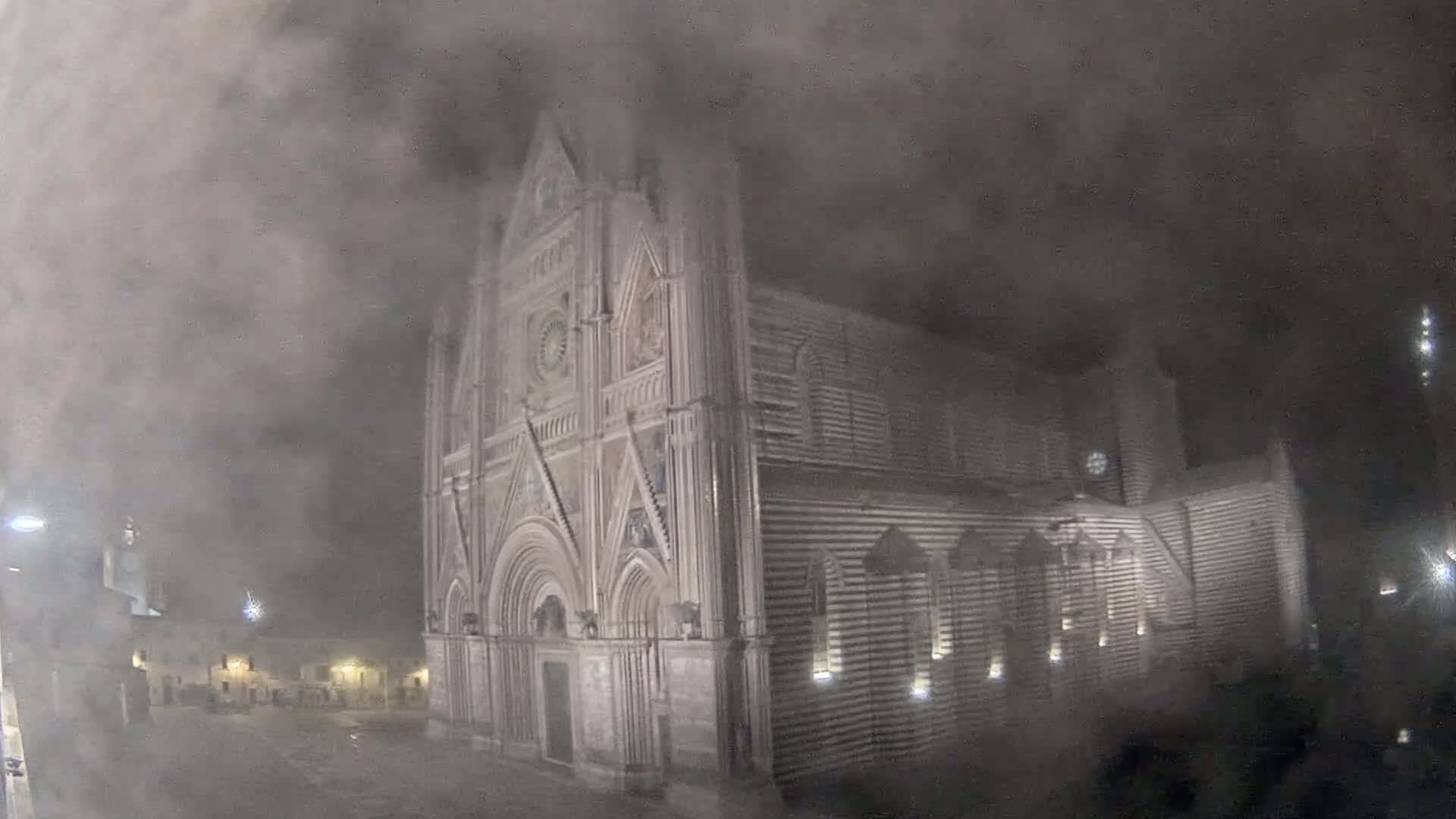 A large, ornate stone cathedral is shrouded in thick fog at night.
