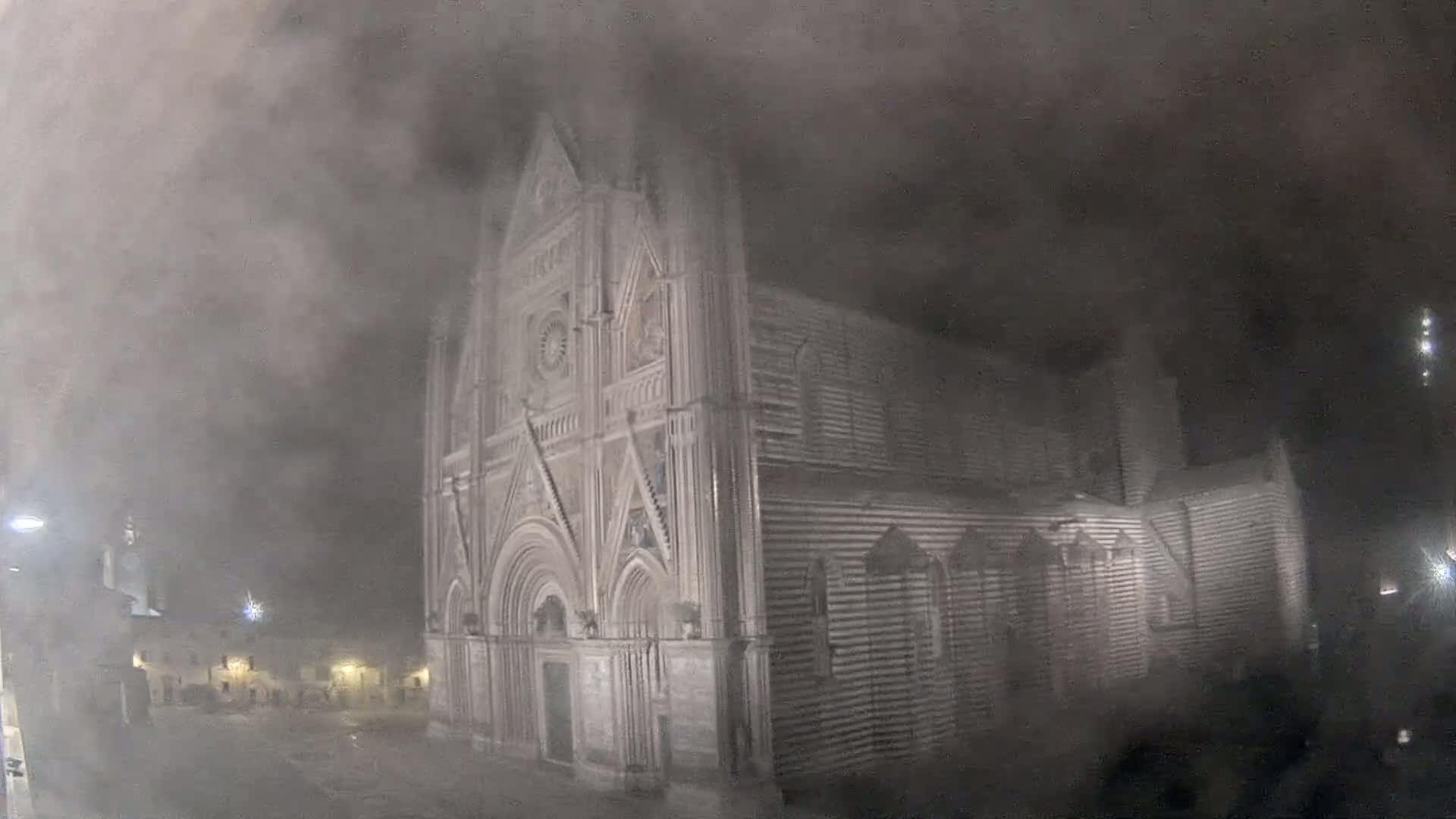 A large stone cathedral is shrouded in thick fog at night.