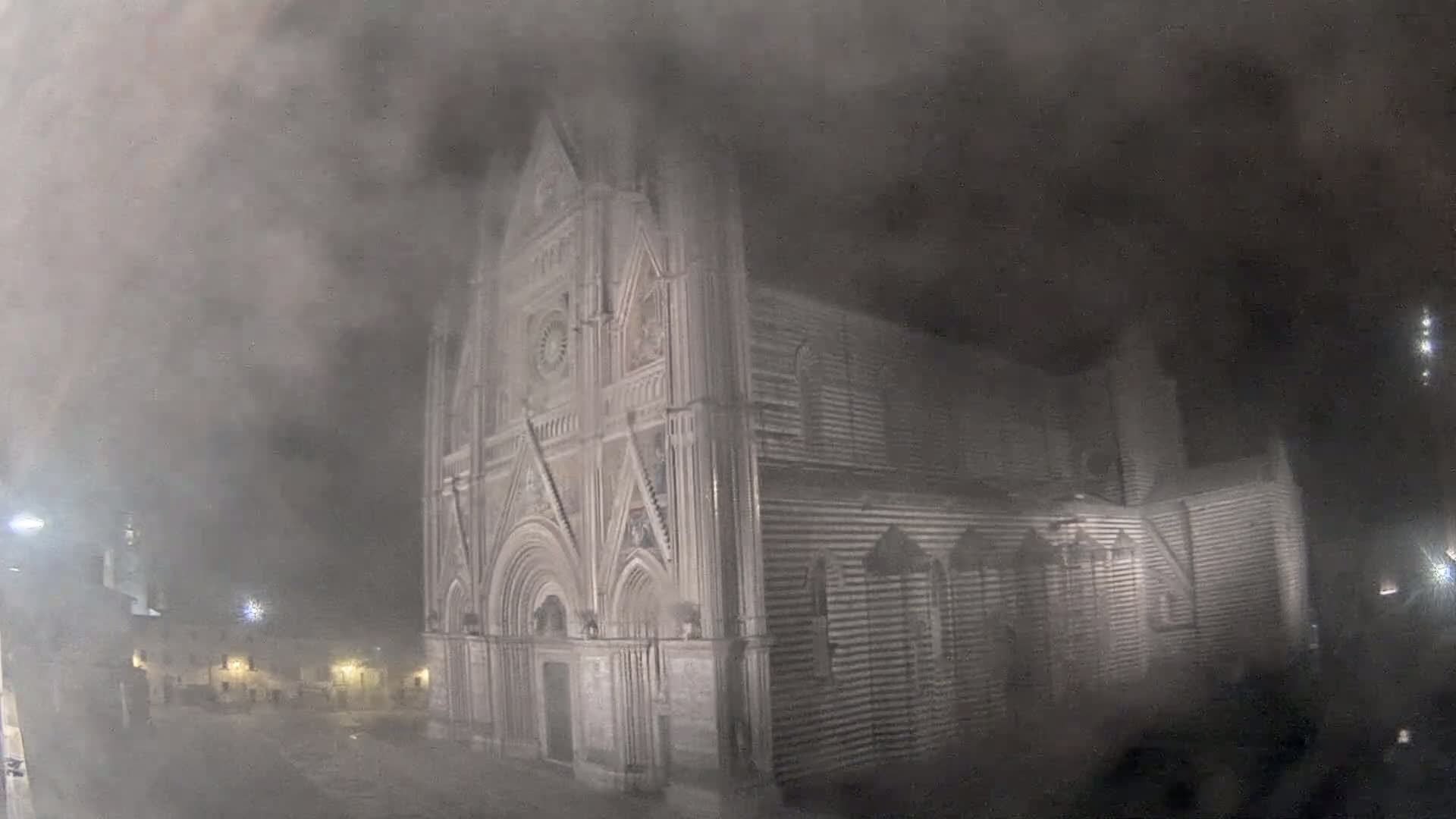 A large stone church is shrouded in heavy fog at night.