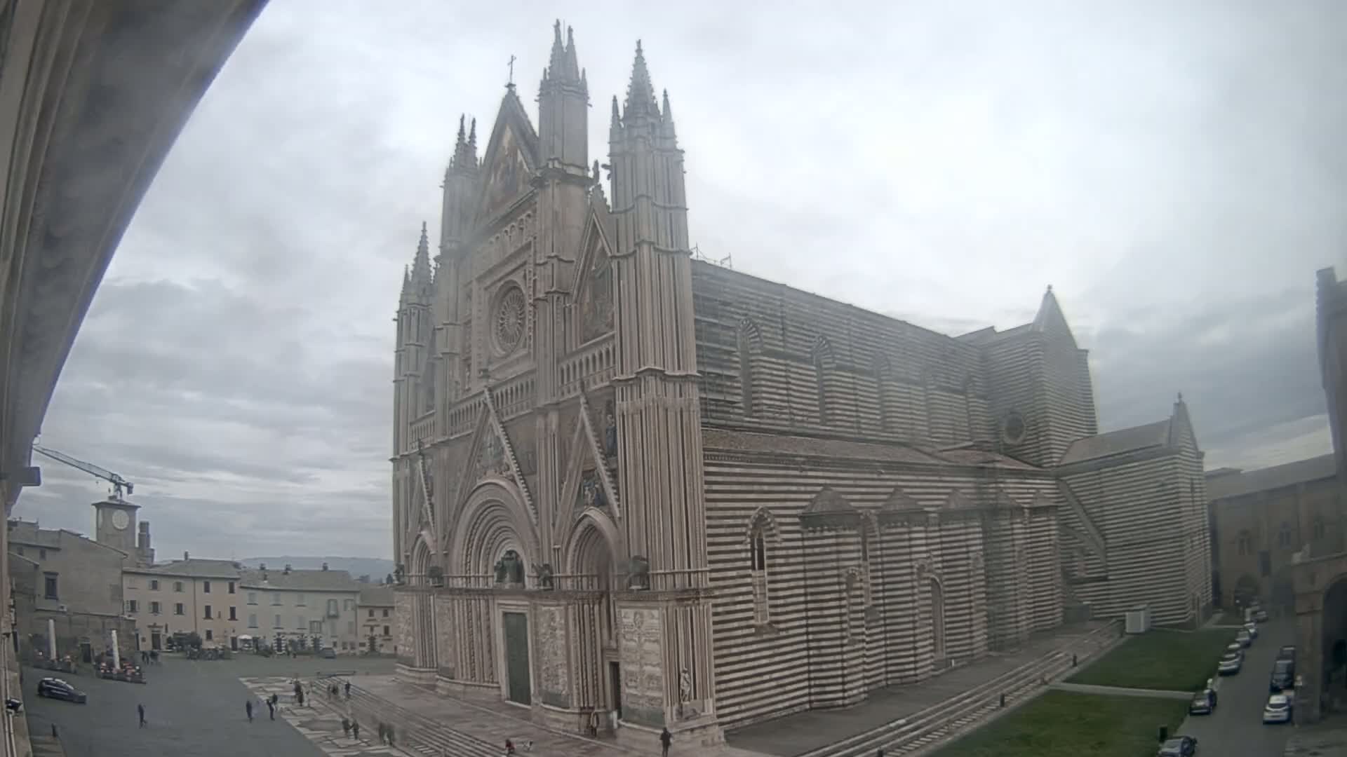 A large striped cathedral stands in a town square on an overcast day.