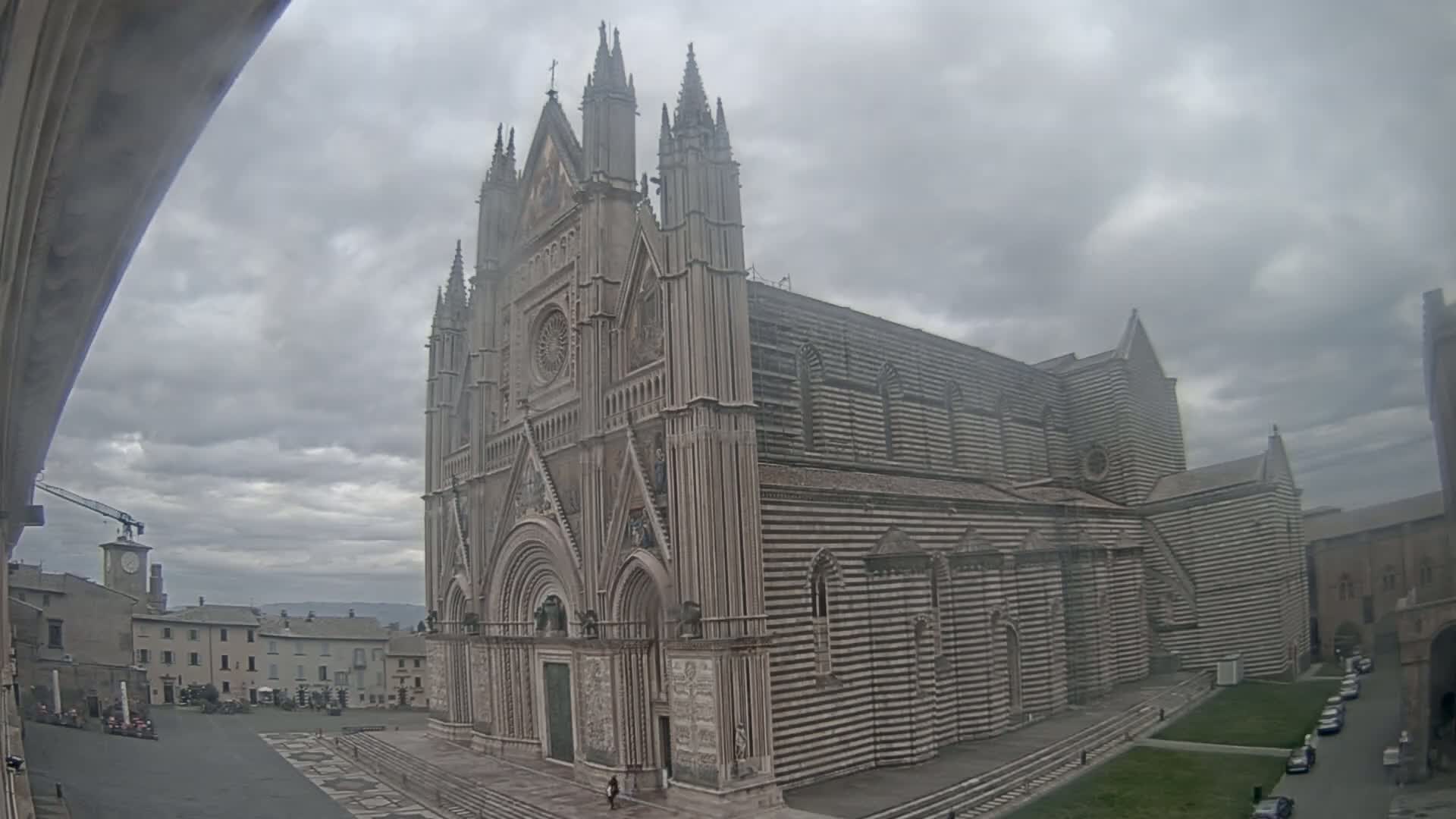 A large, striped cathedral stands in a town square on an overcast day.