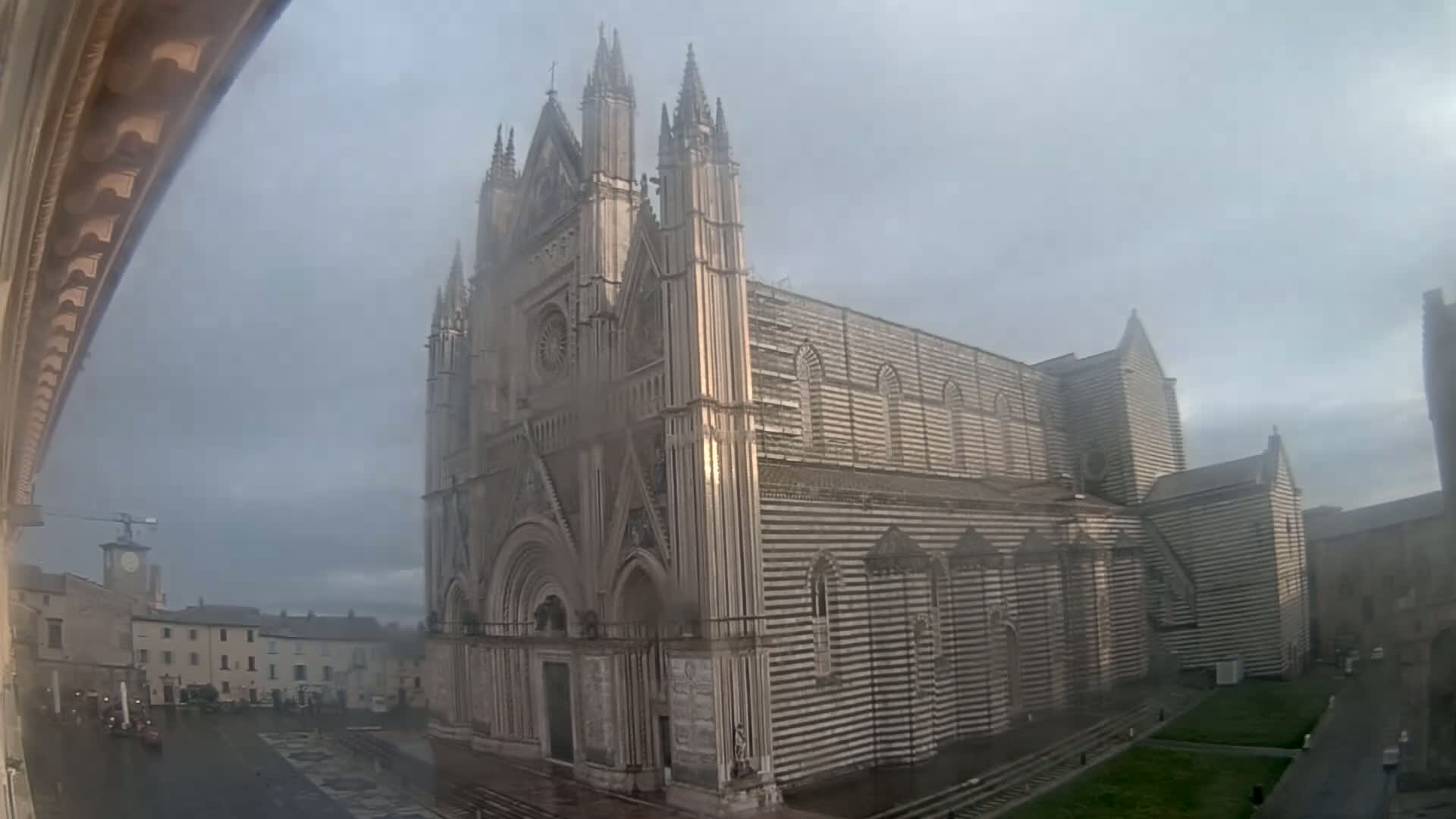 A large, striped cathedral stands in a town square on an overcast day.