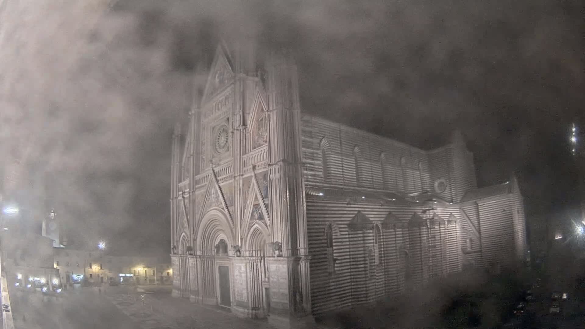 A large, striped cathedral stands shrouded in dense fog at night.