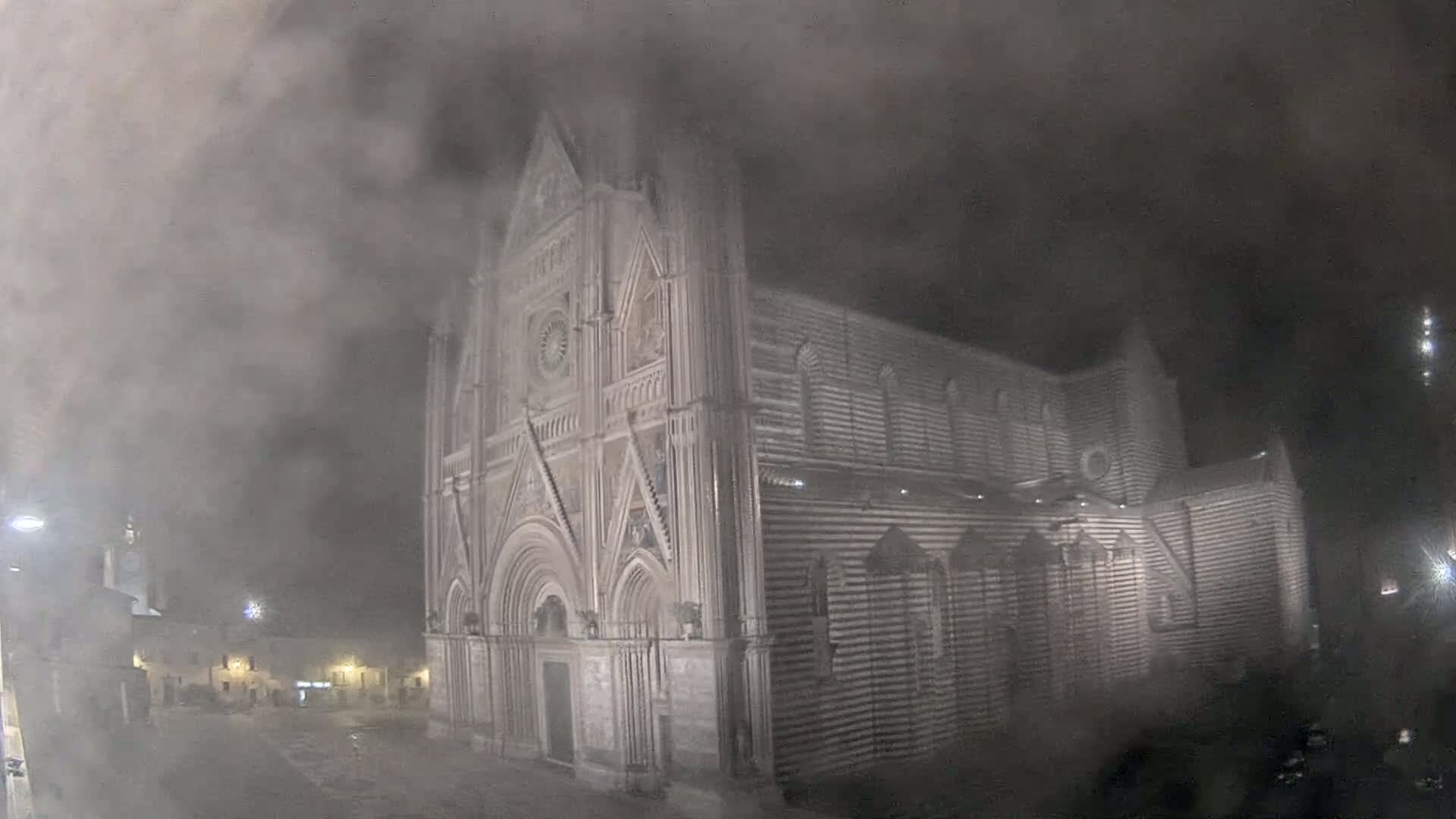 A large stone cathedral is shrouded in thick fog at night.