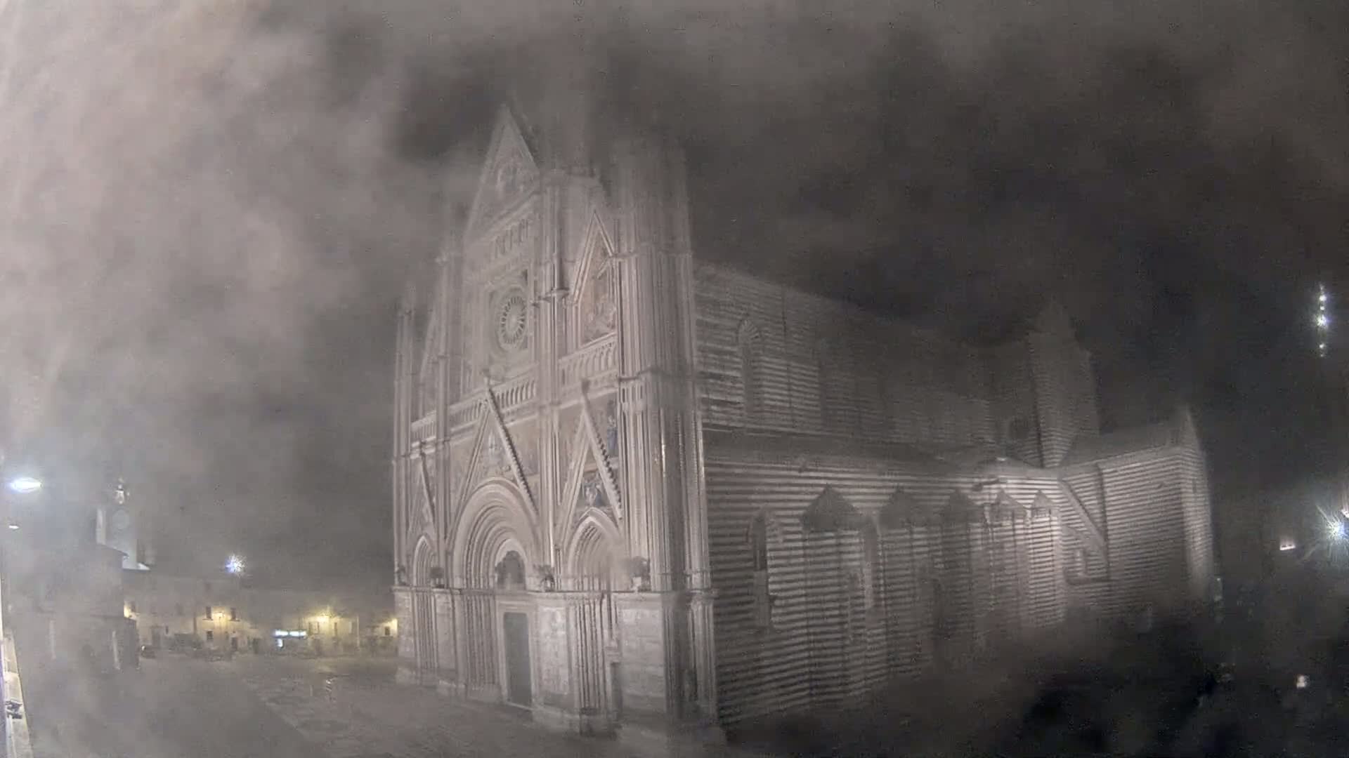 A large stone cathedral is shrouded in a thick fog at night.