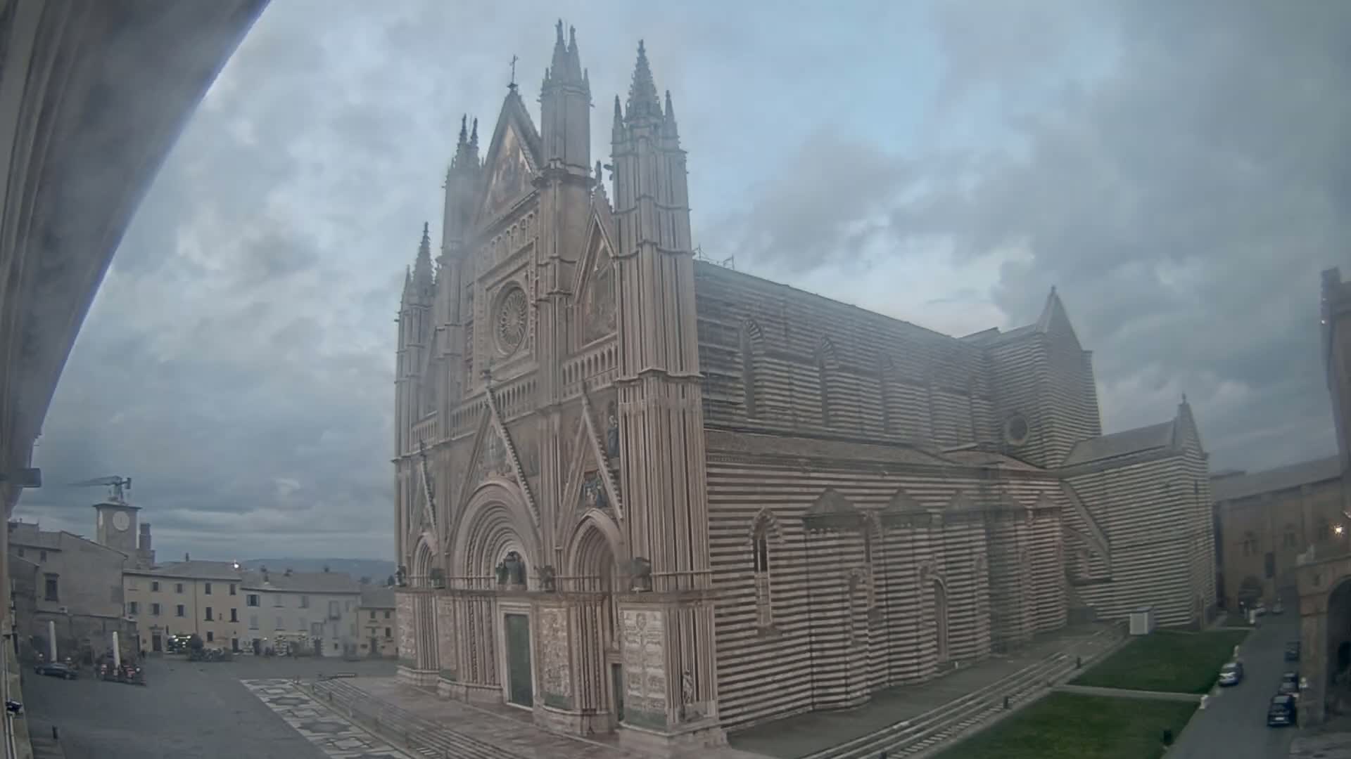 A large striped cathedral stands in a town square under an overcast sky.
