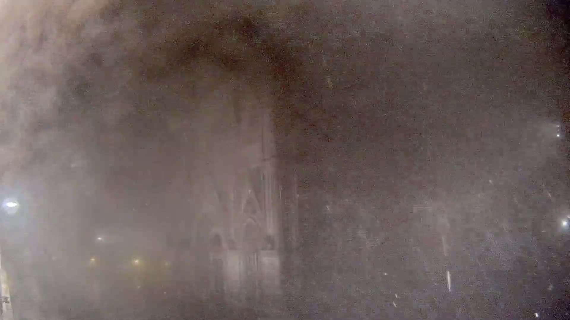 A large, dark building is barely visible through heavy snowfall at night.
