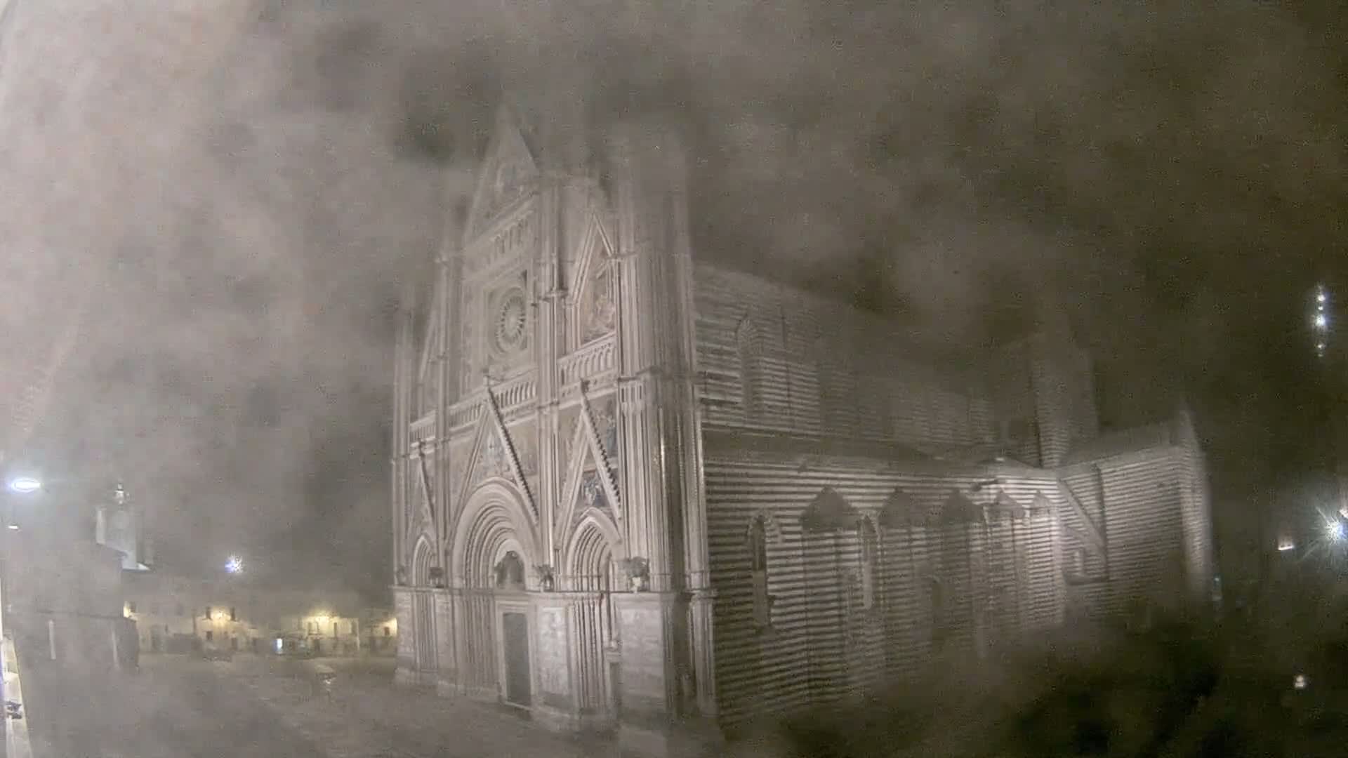 A large, striped stone cathedral is visible at night through a thick fog or mist.