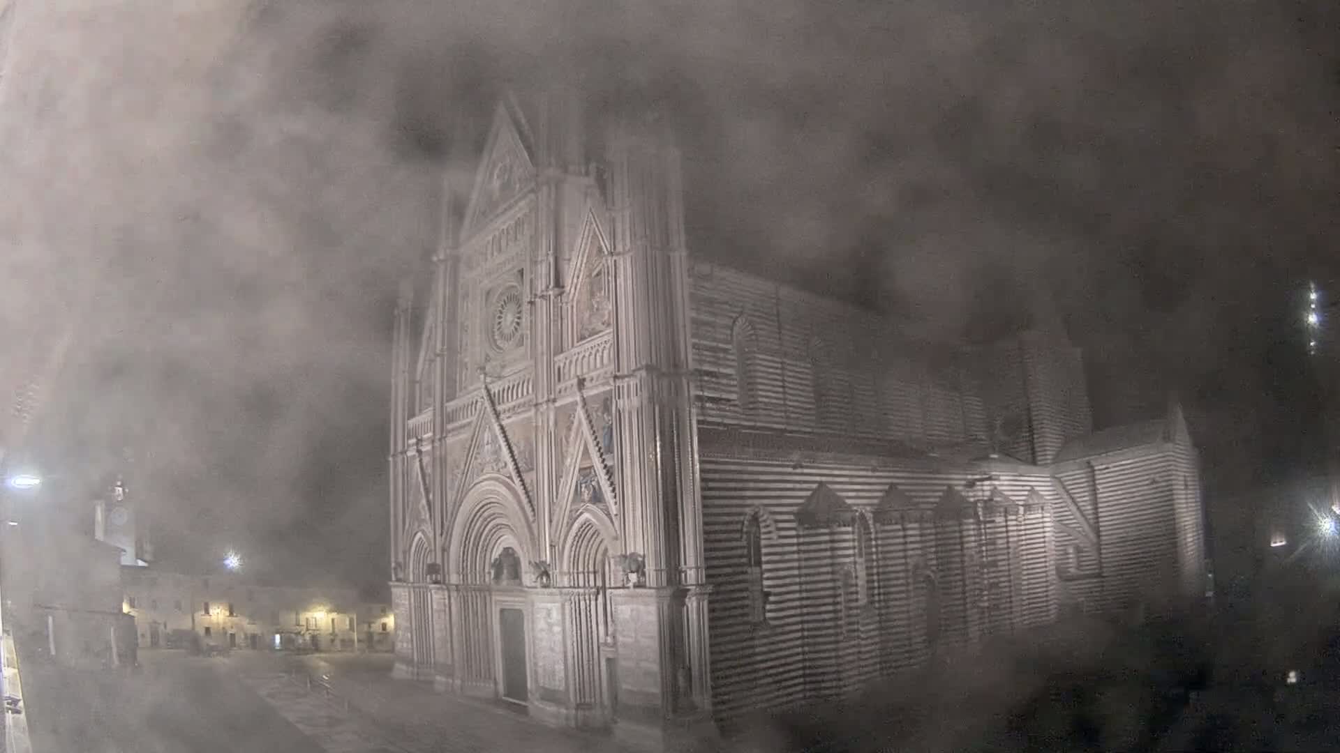 A large, striped cathedral is partially obscured by a thick fog at night.