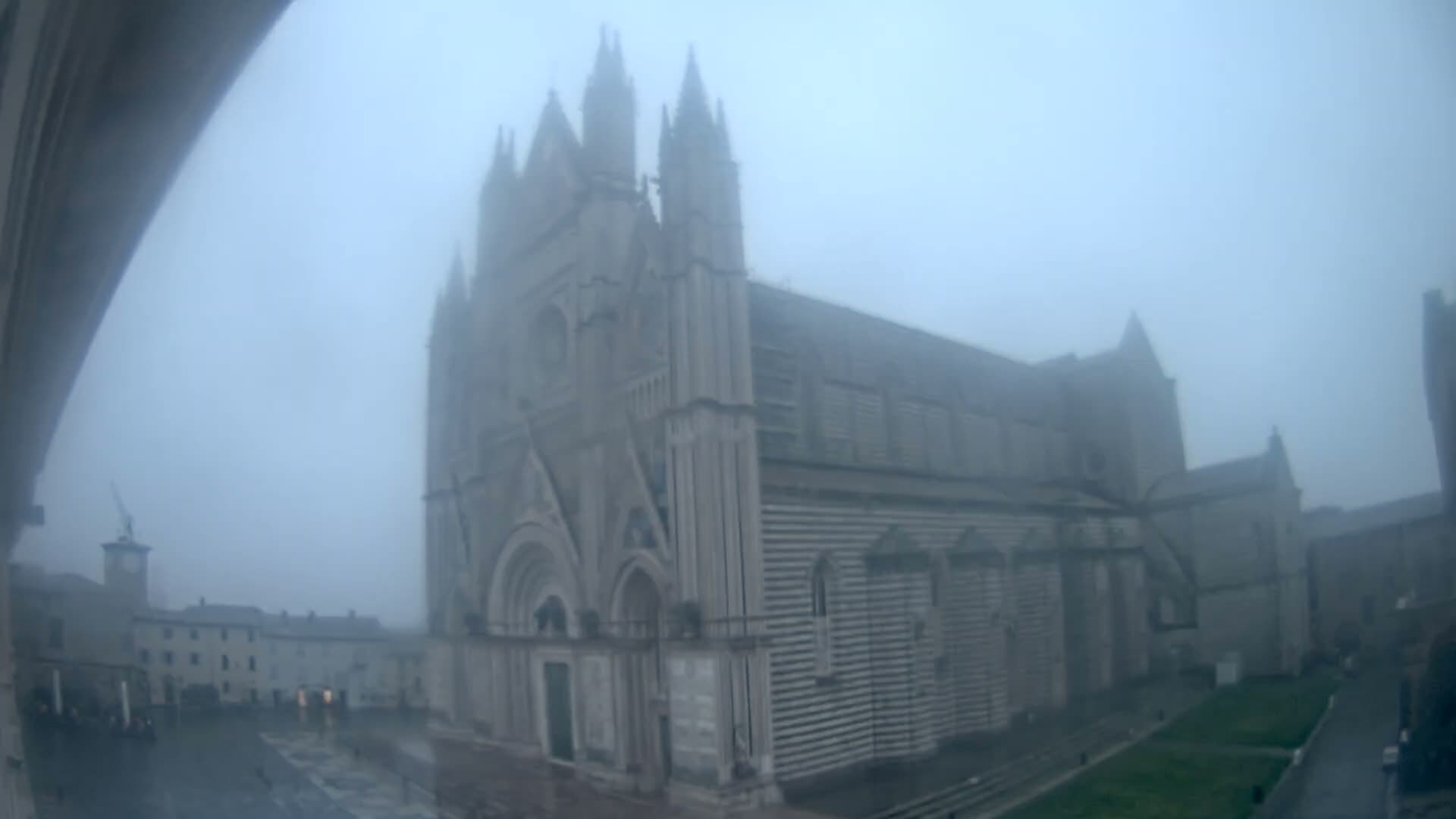 A large stone cathedral is shrouded in a thick fog.