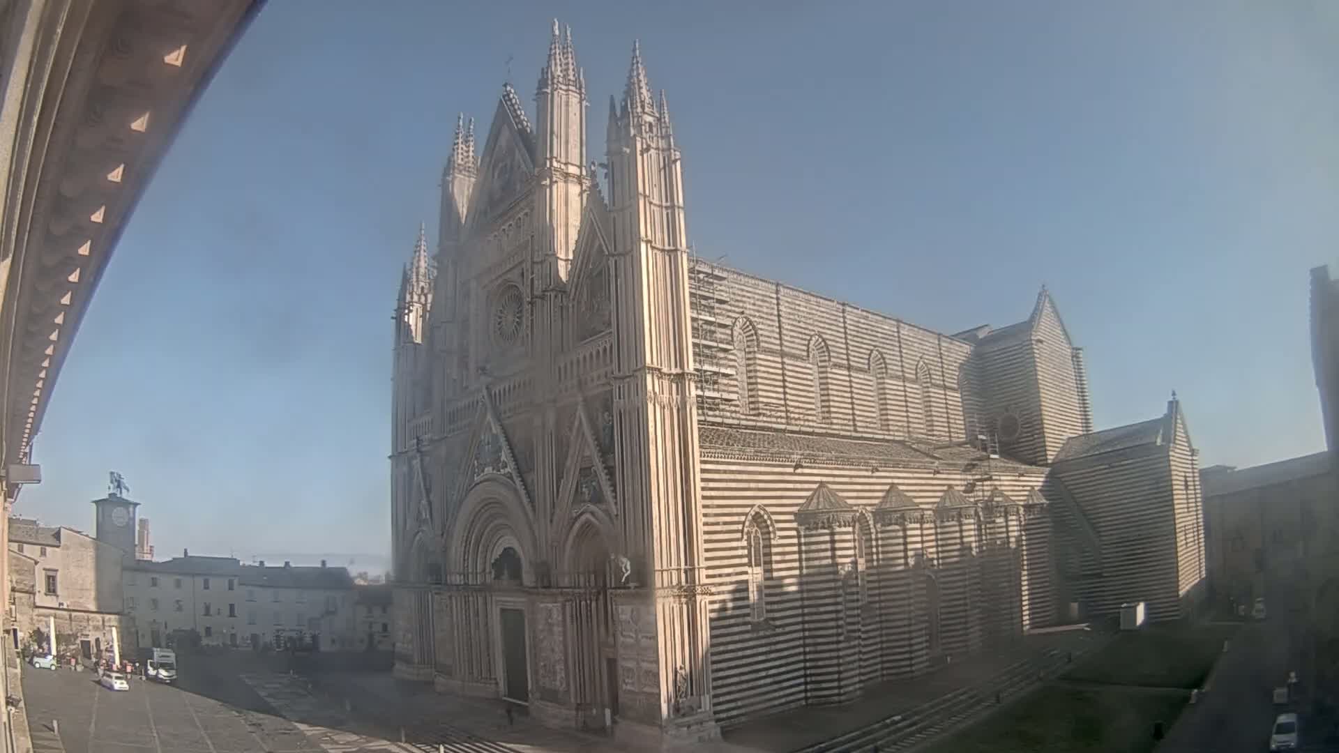 A large striped cathedral stands in a city square on a sunny day.