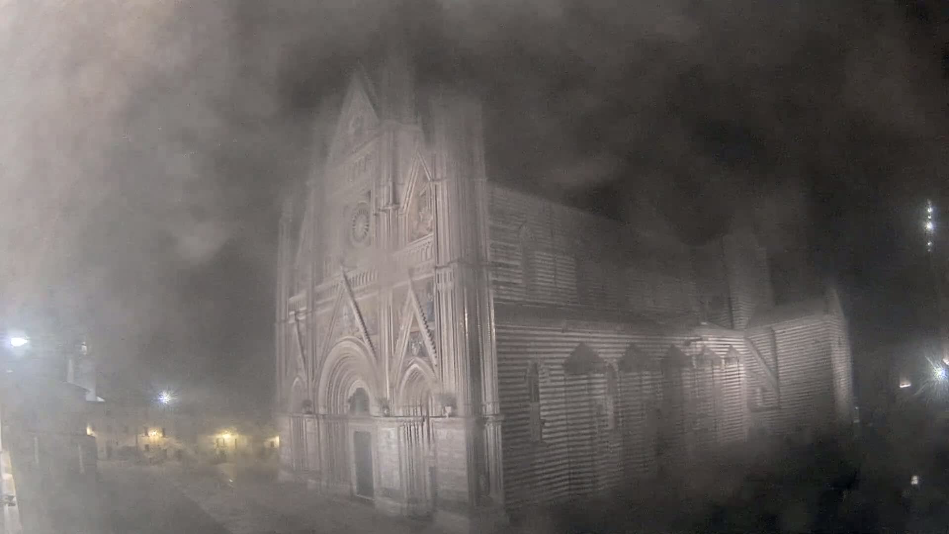 A large stone cathedral is shrouded in heavy fog at night.