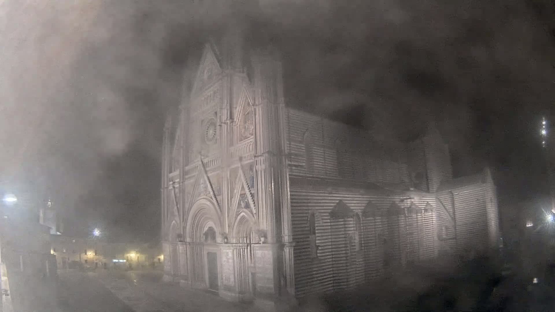 A large stone cathedral is partially obscured by heavy fog at night.