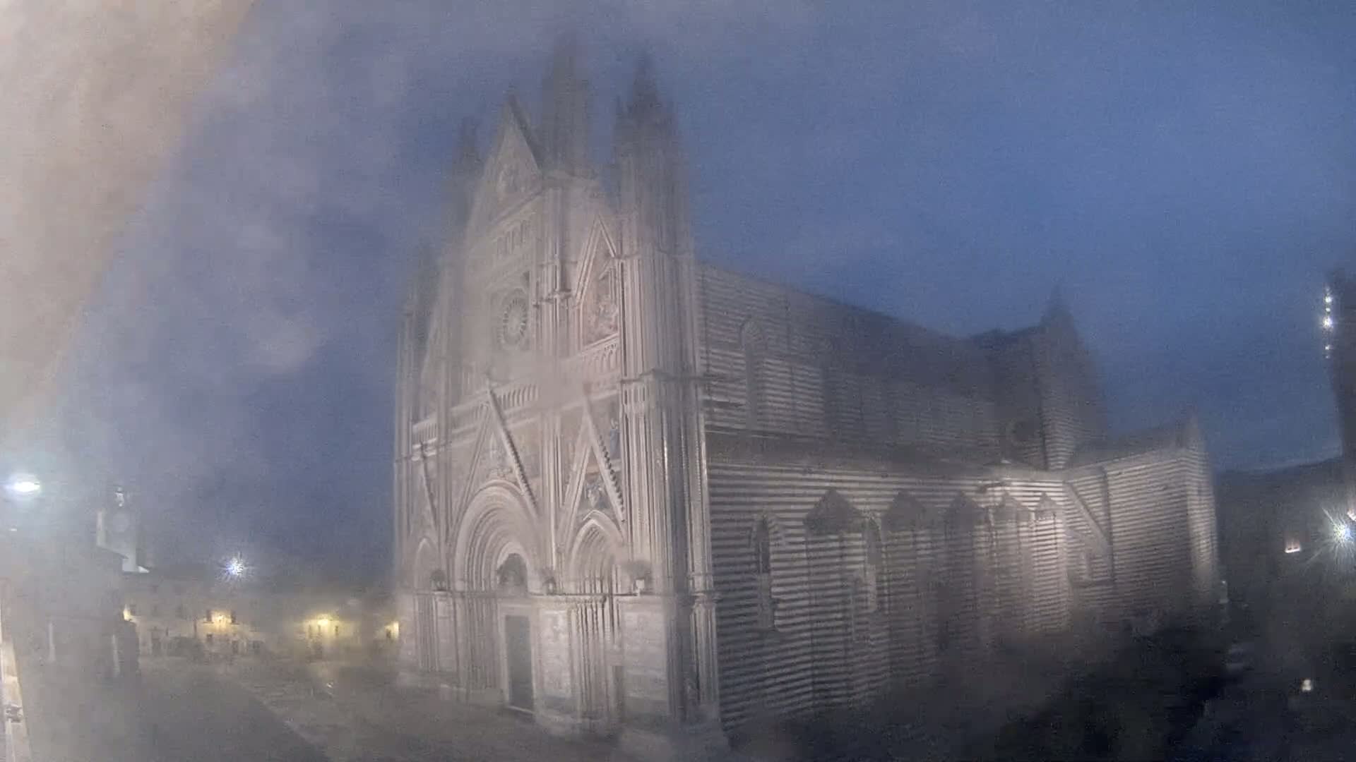 A large, striped stone cathedral is visible at night through a hazy, foggy atmosphere.