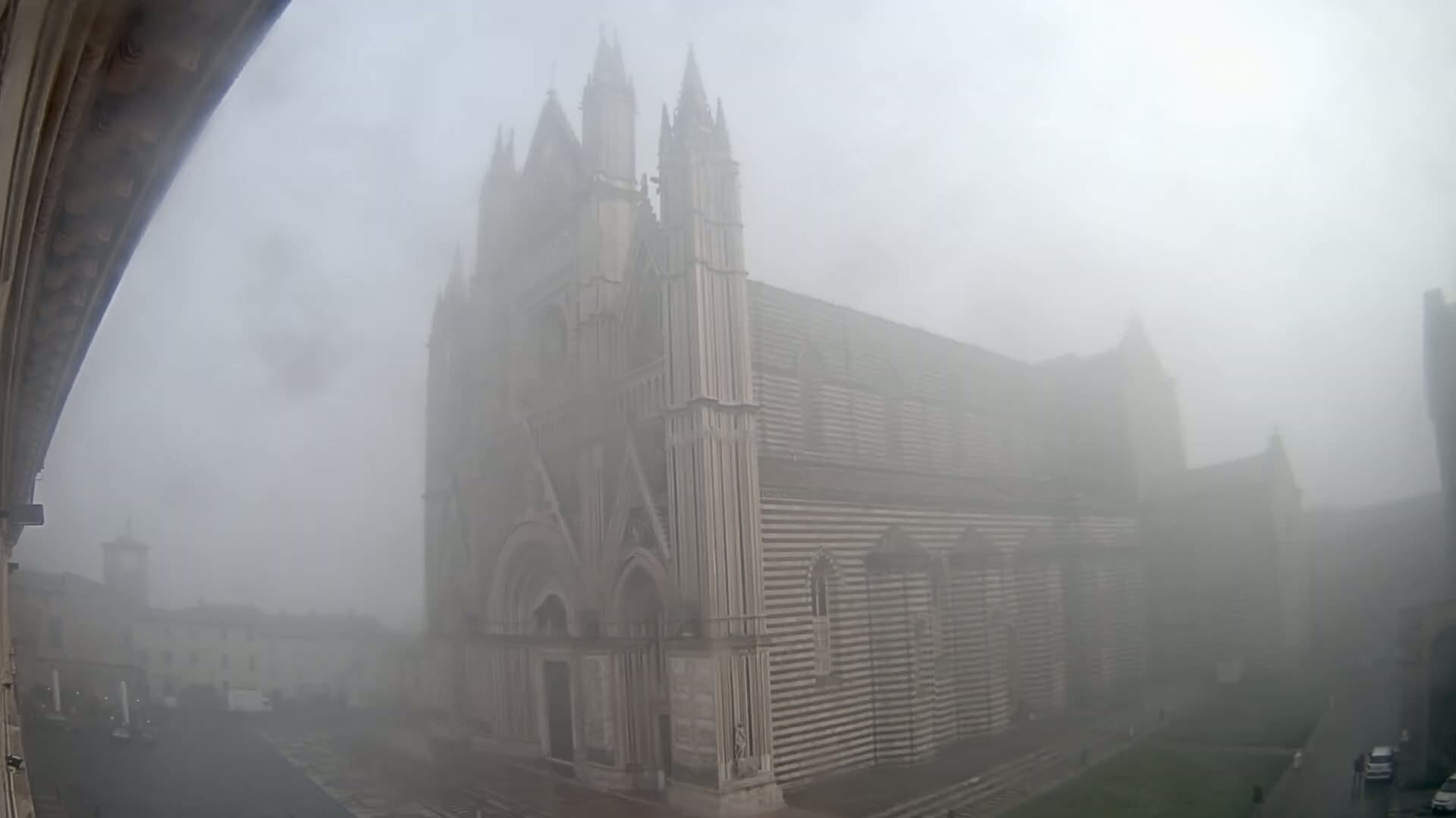 A large, striped cathedral stands shrouded in heavy fog.