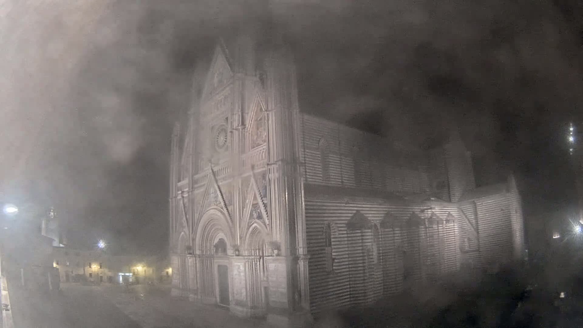 A large, ornate stone cathedral is visible at night, shrouded in a thick fog or dust.