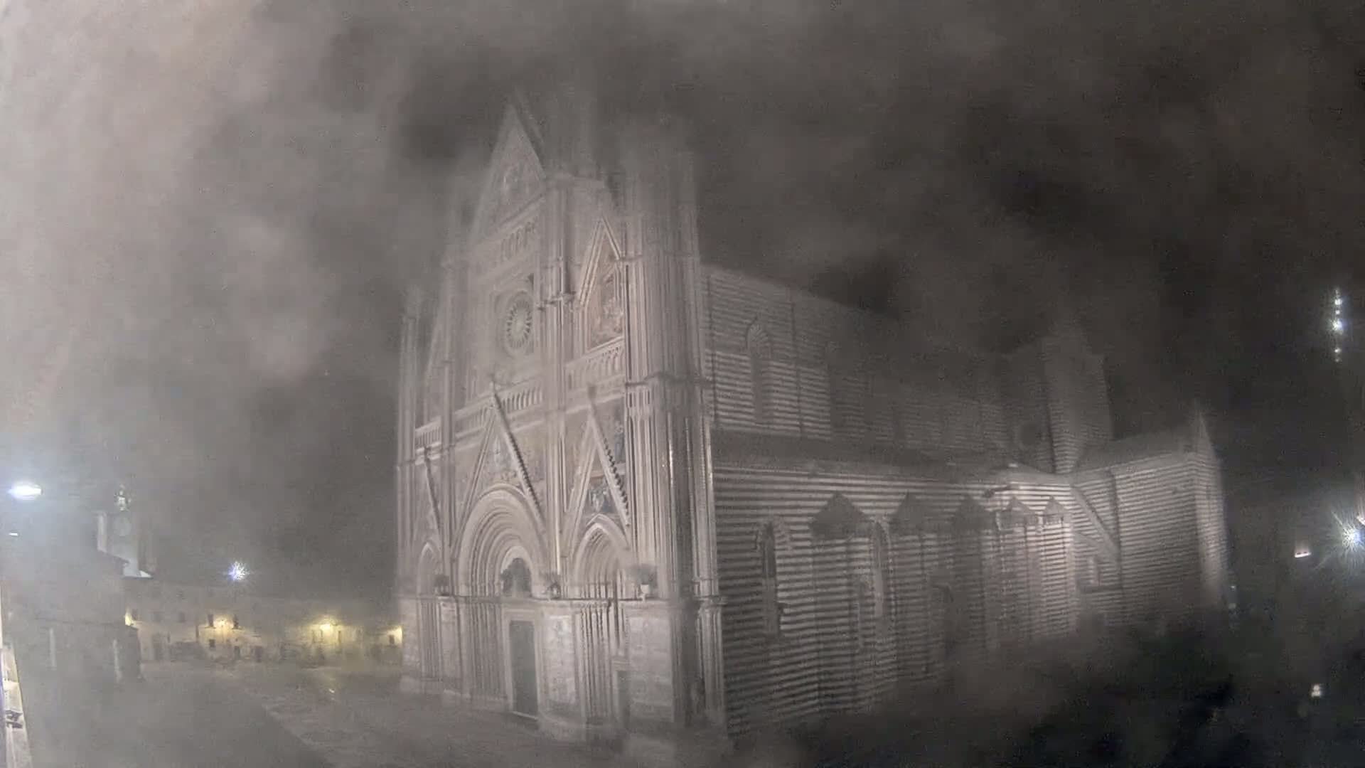 A large, ornate cathedral is partially obscured by a thick fog at night.
