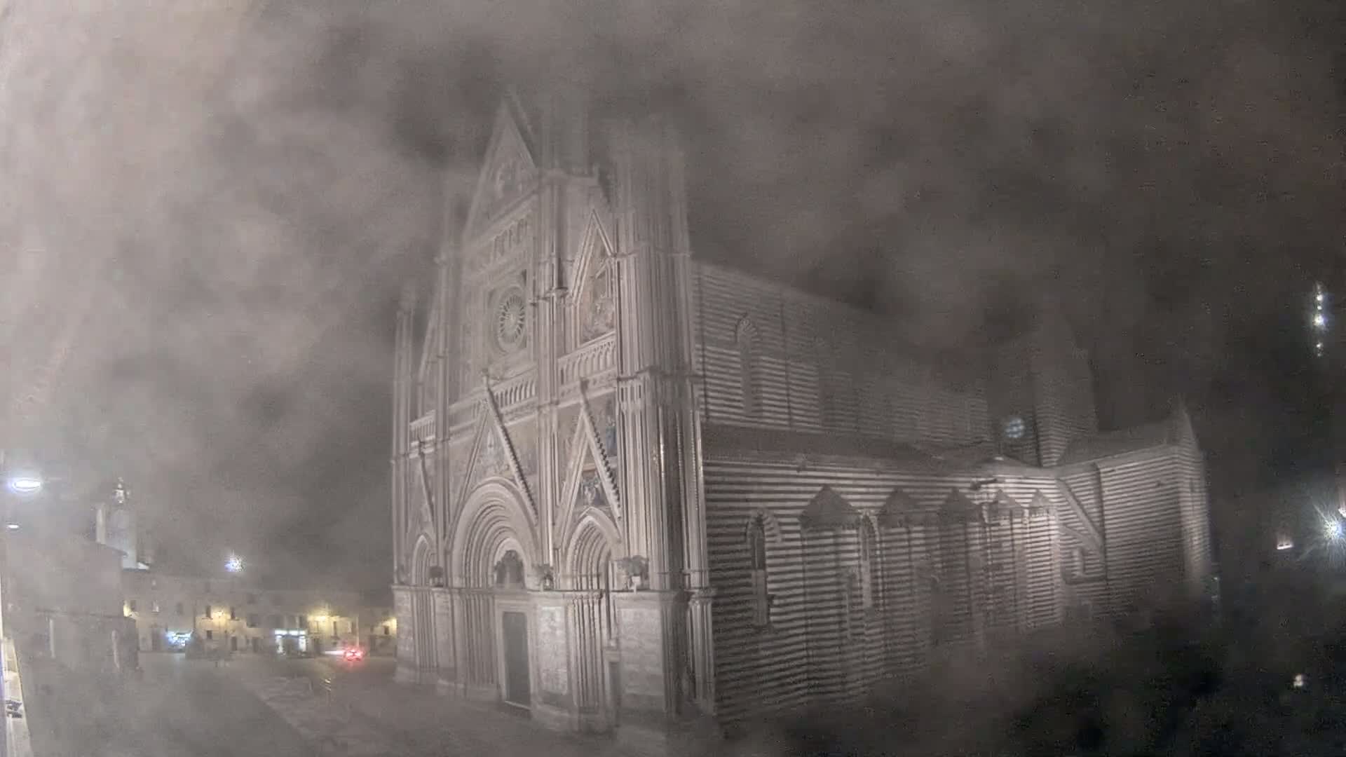 A large, striped stone cathedral is shrouded in thick fog at night.