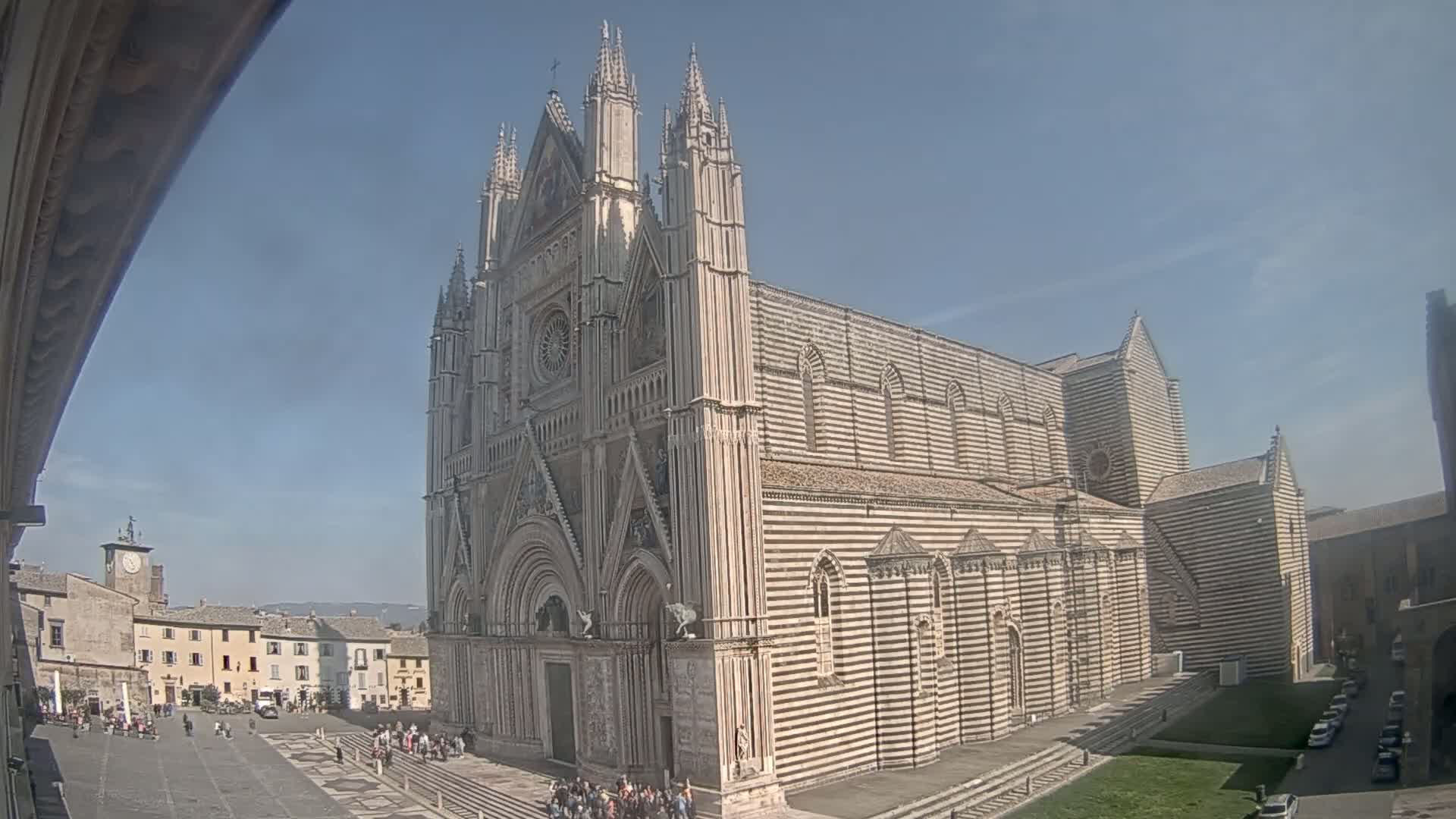 A large striped cathedral stands in a town square on a sunny day.
