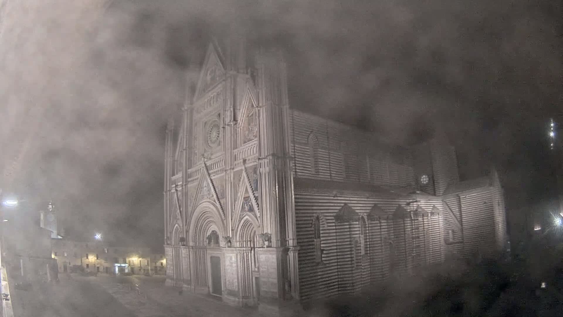 A large, striped cathedral is shrouded in a thick fog at night.