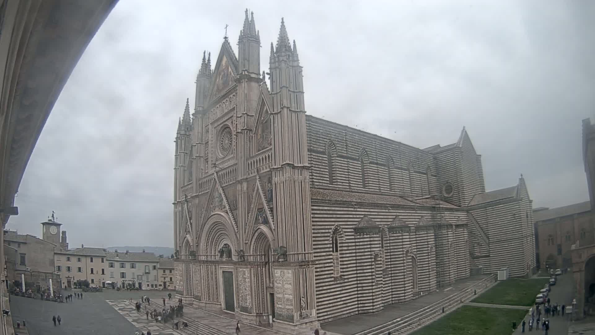 A large, striped cathedral stands in a town square on an overcast day.
