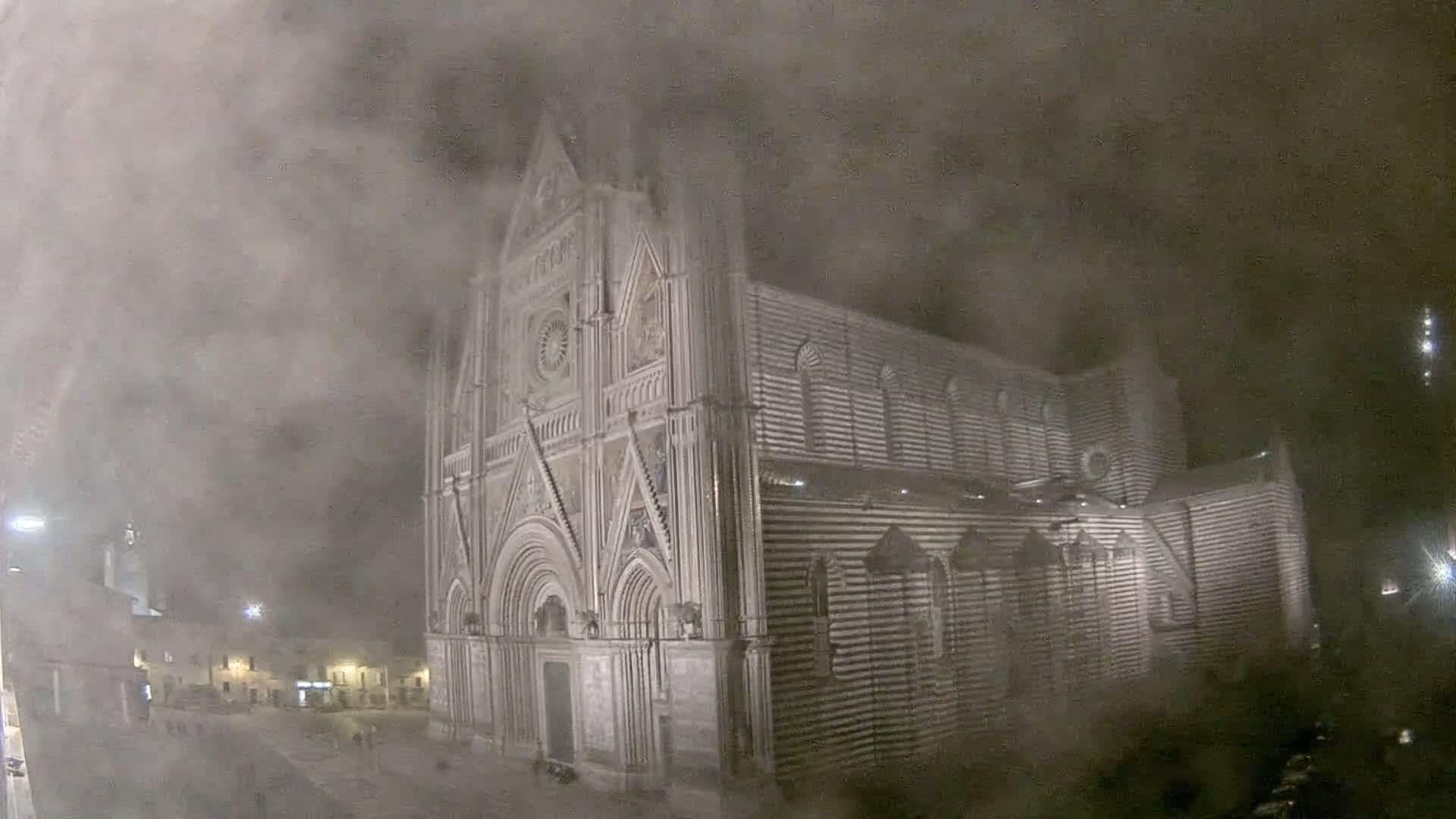 A large, striped cathedral is partially obscured by a thick fog at night.