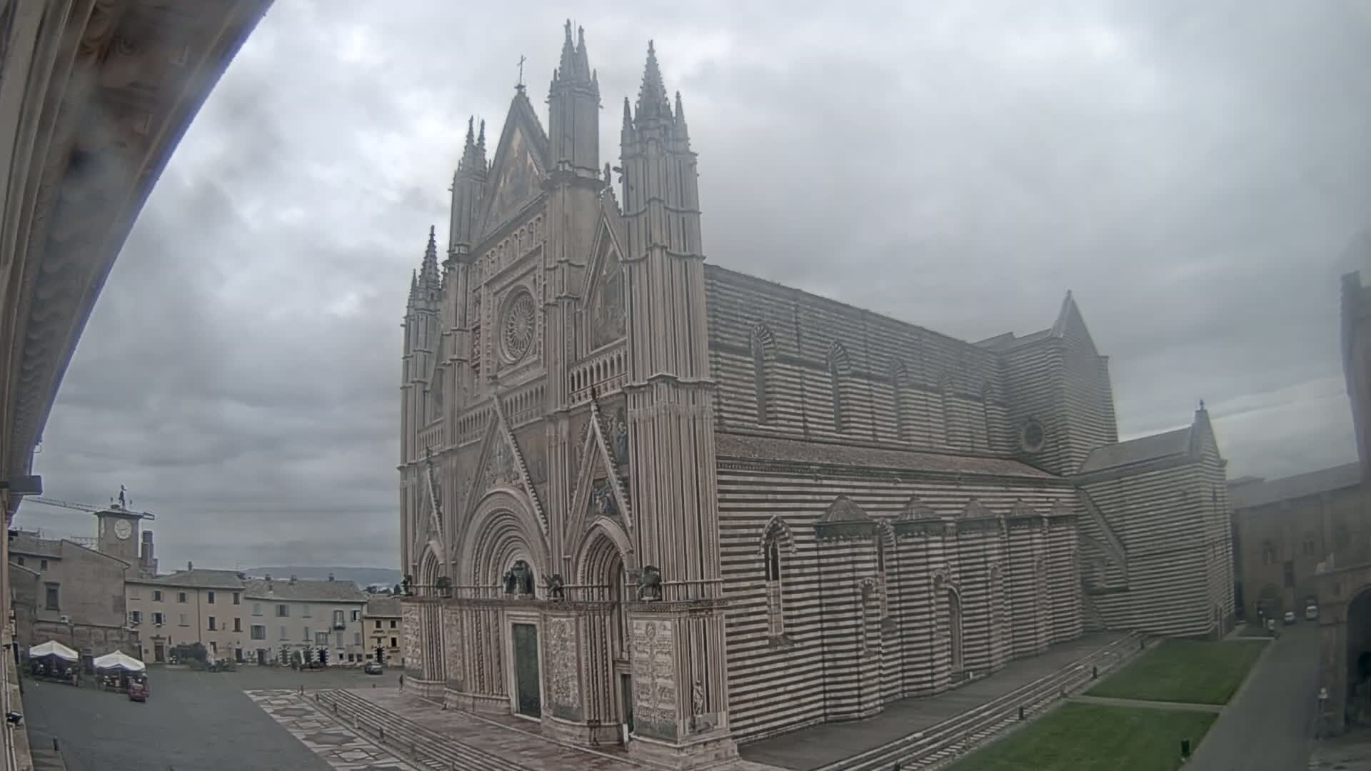 A large, striped cathedral stands in a town square on an overcast day.