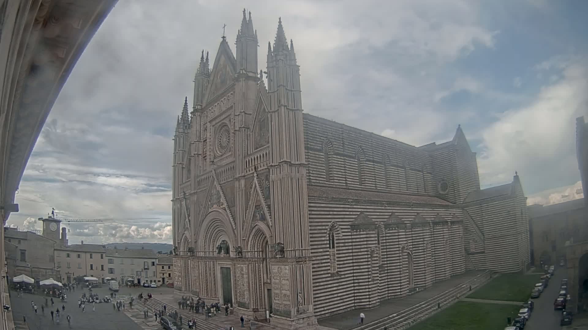 A large, striped cathedral stands in a town square on an overcast day.