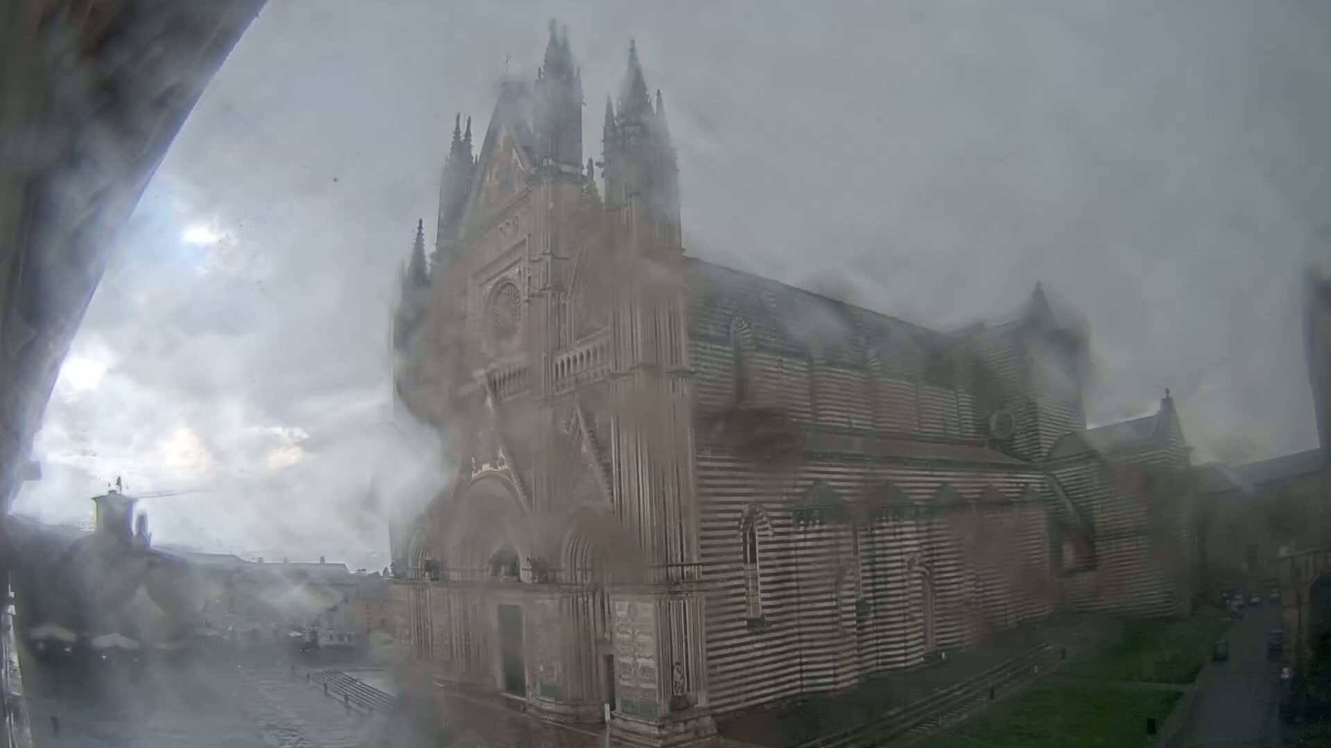 A large, striped cathedral is seen through rain-streaked glass during an overcast day.