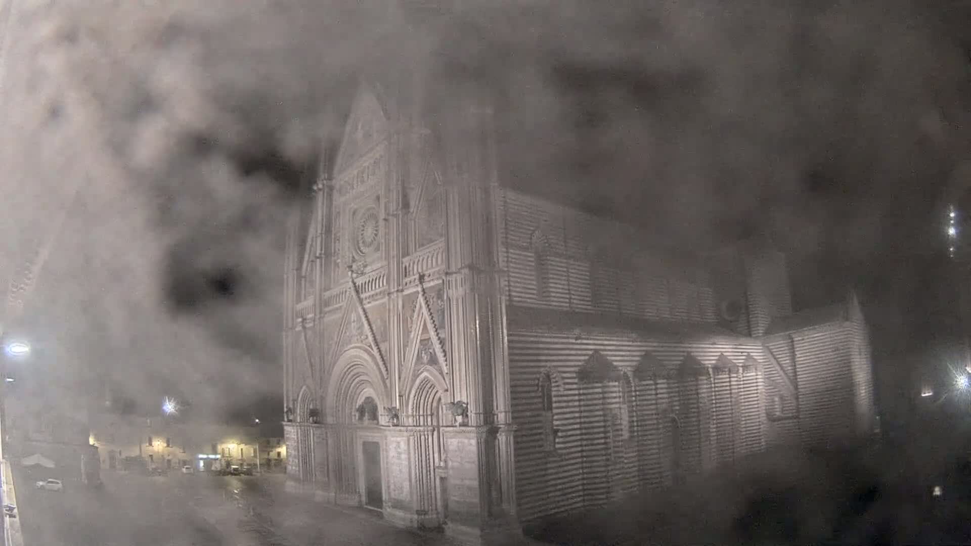 A large stone cathedral is partially obscured by heavy fog at night.