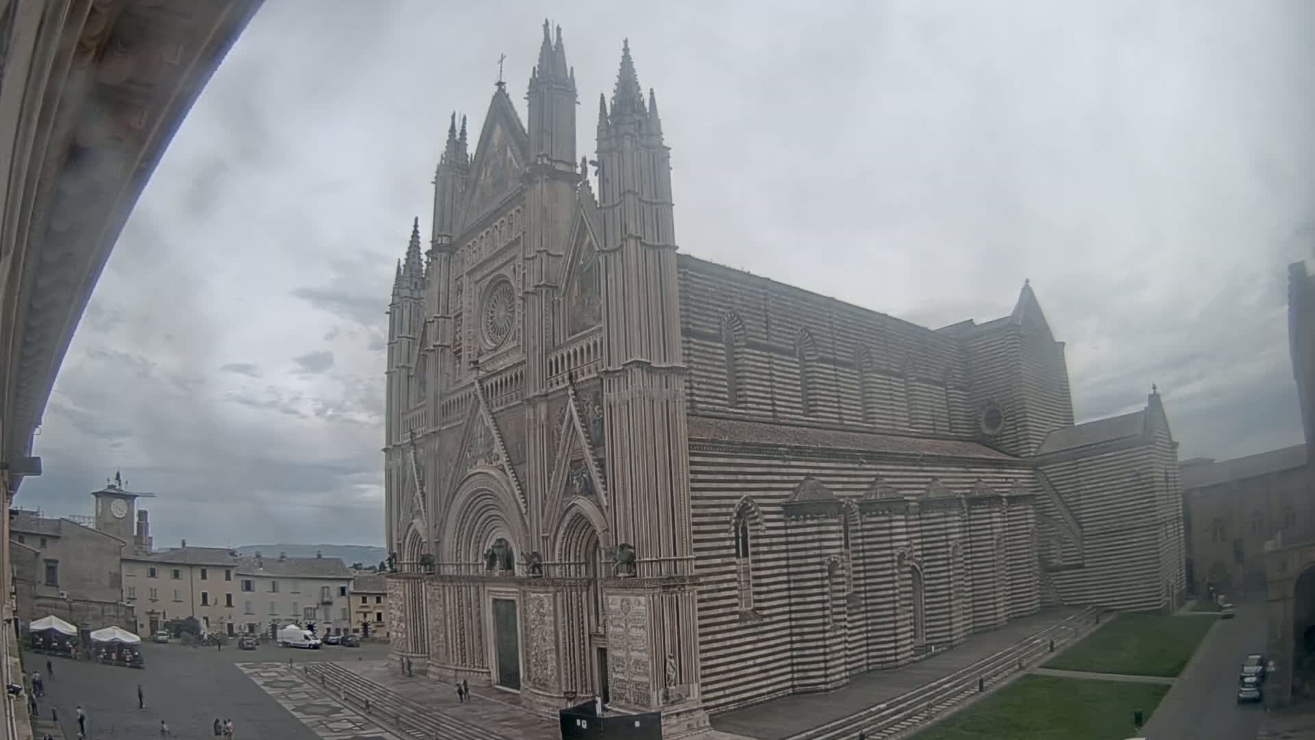 A large, striped cathedral stands in a town square on an overcast day.