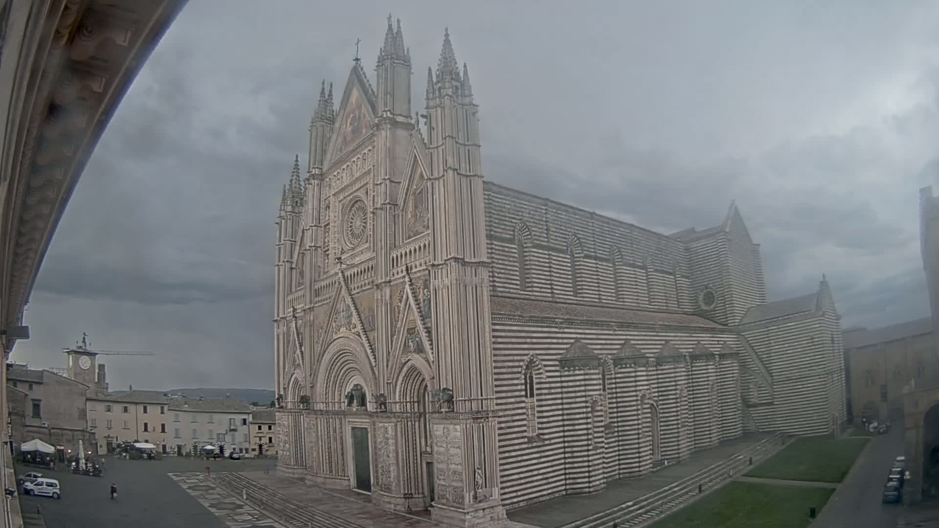 A large, striped cathedral stands in a town square under an overcast sky.