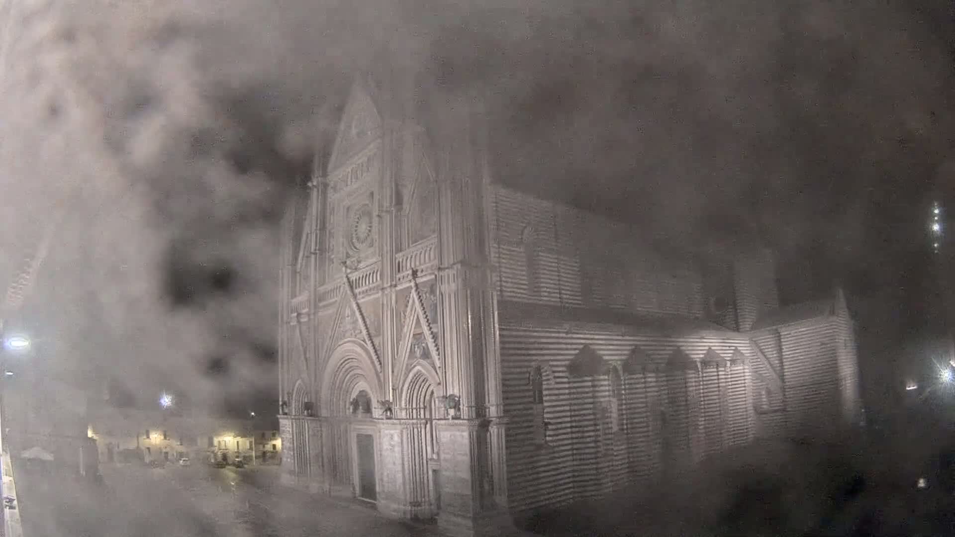 A large, gothic-style cathedral is partially obscured by a thick fog at night.